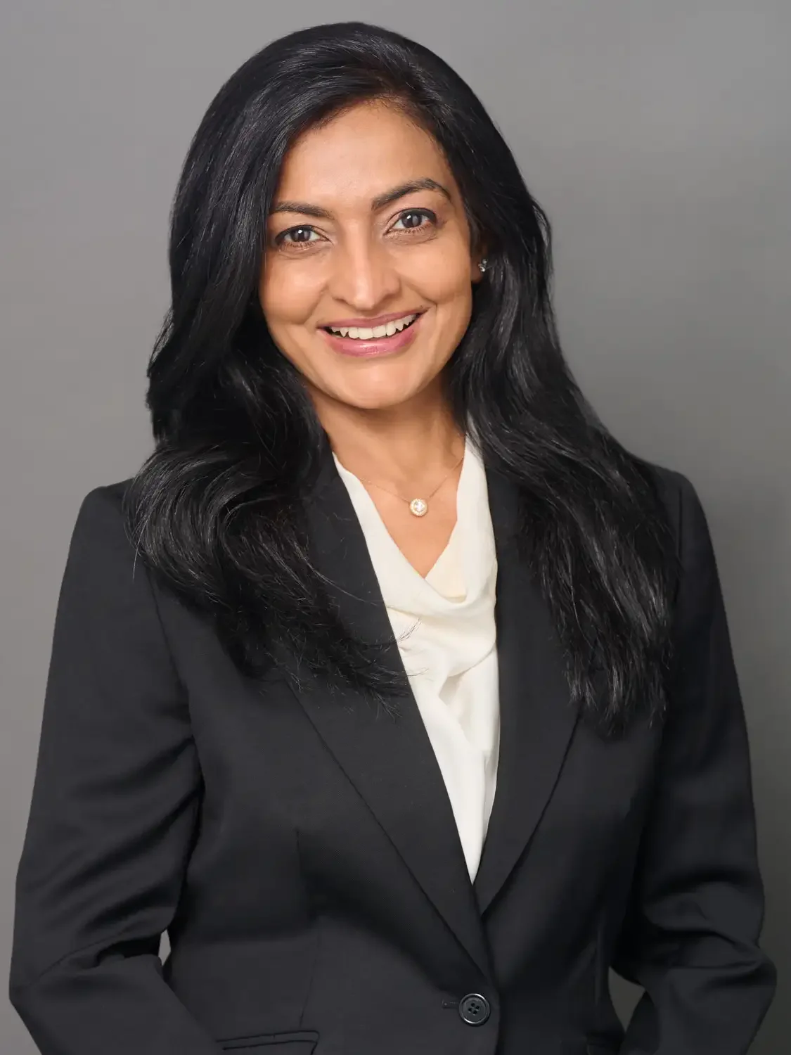 Professional portrait of a female CEO in a tailored black suit photographed in a professional photo studio.
