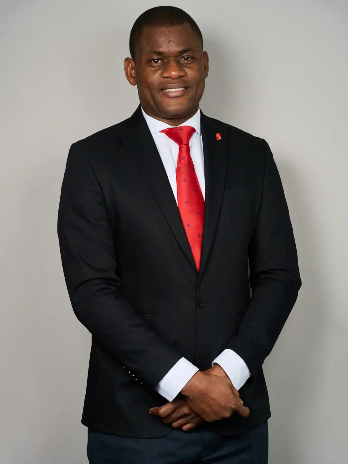 Headshot of a bank executive in a black suit with a white shirt and red tie photographed in a professional photo studio.