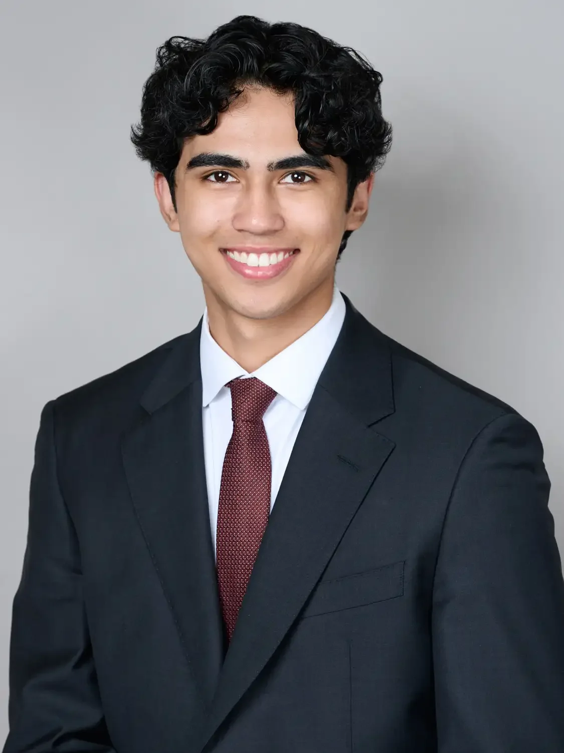 Portrait of a  young man with dark, curly hair  for LinkedIn headshot.