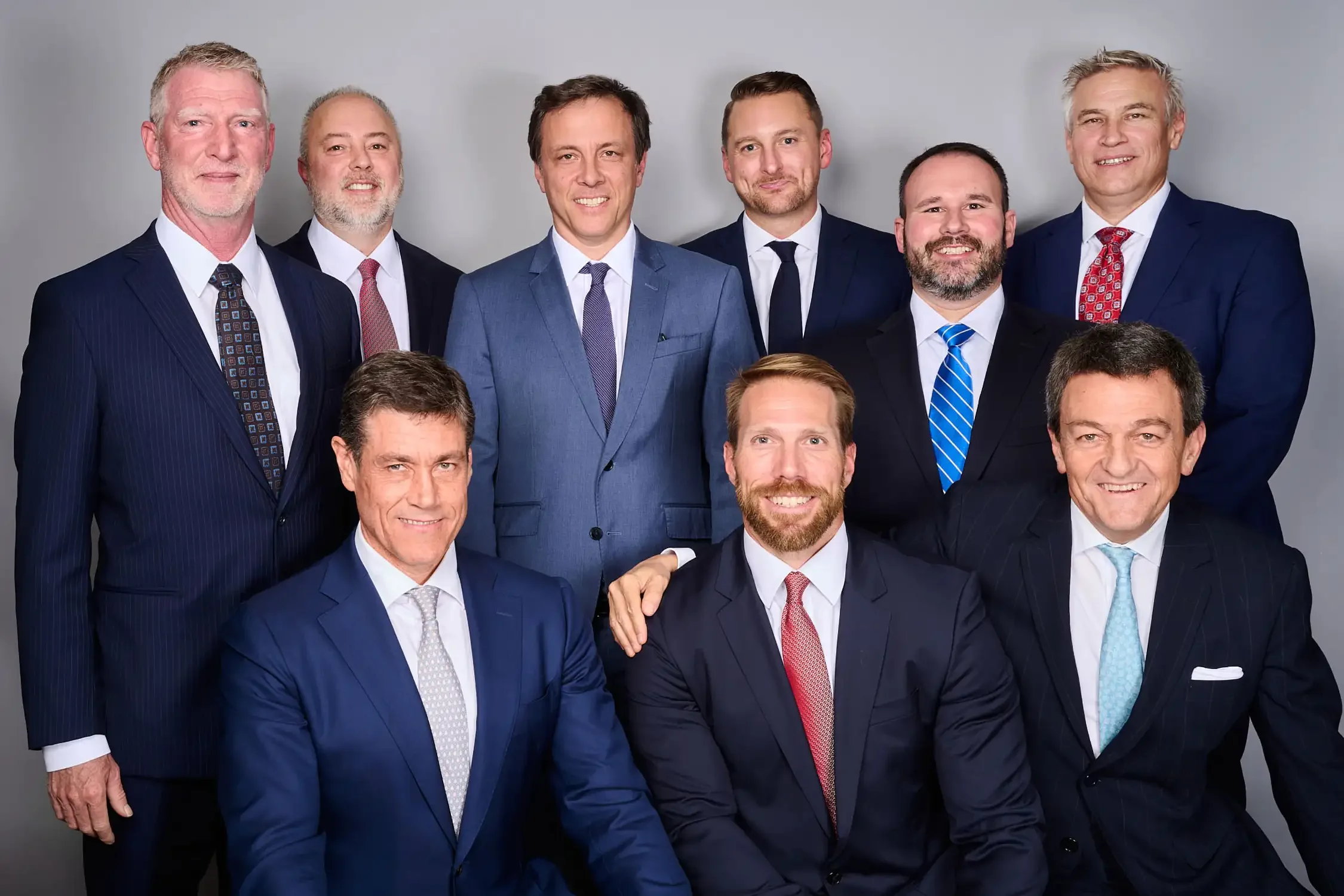 Headshots for a team of nine executives  dressed in formal business suits posing together in a photo studio New-York.