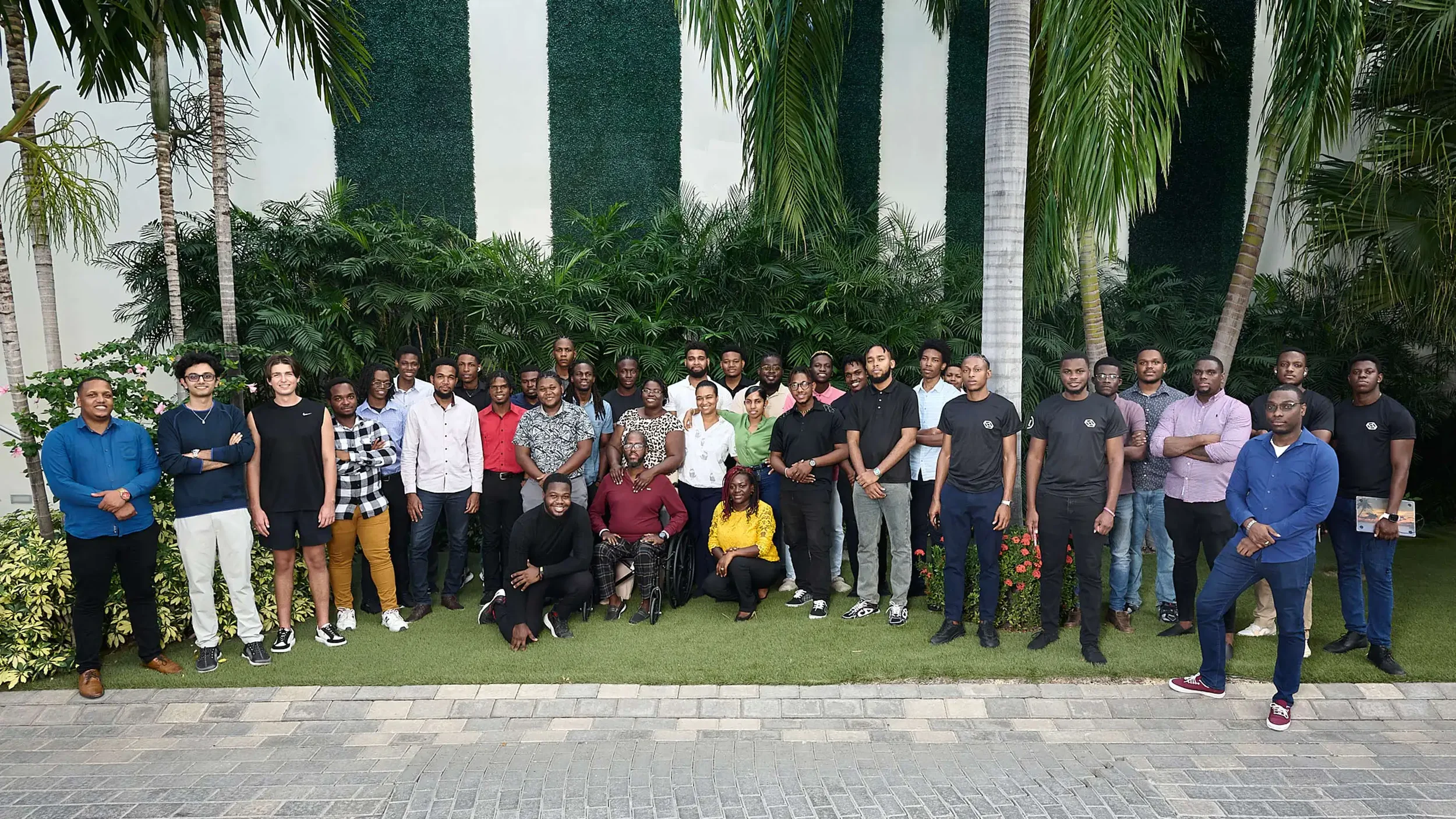 Professional corporate group shot for a team  of forty people gathered outdoors in front of greenery.