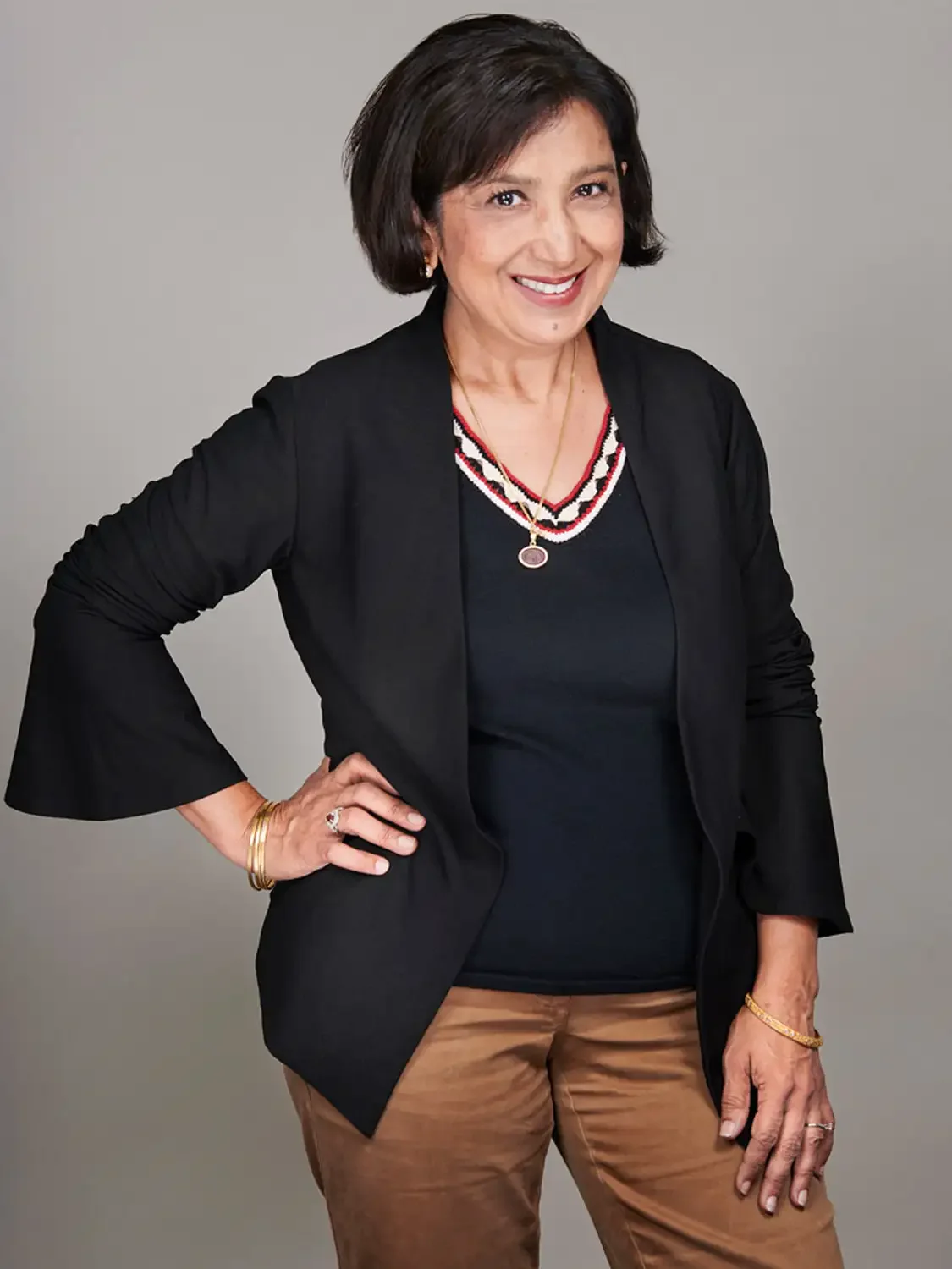 Professional headshot of a woman with short dark hair smiling, photographed in a professional photo studio.