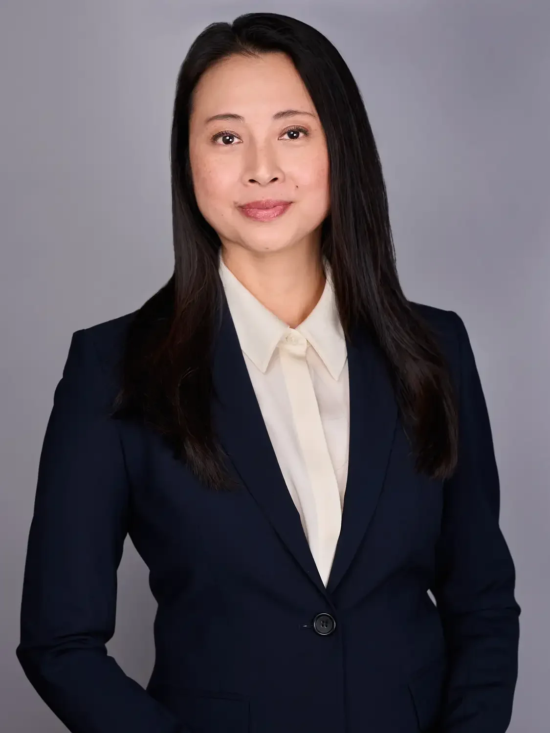Professional headshot session for an Asian woman with long dark hair wearing a navy blazer and white shirt, looking at the camera.