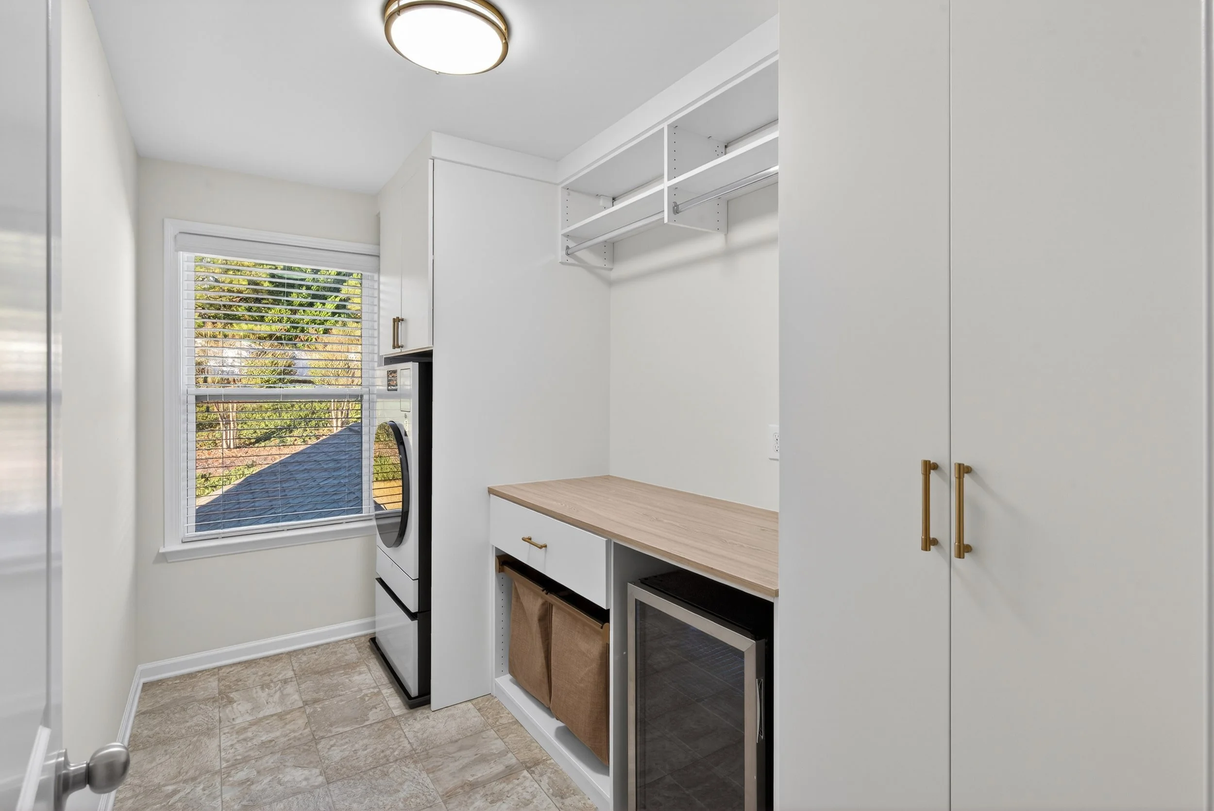 This laundry room proves that even chores can feel luxurious. Designed with clean white cabinetry, warm wood accents, and boutique-style storage, this custom laundry room by Agape Closets brings beauty and function together—so your home works and wow