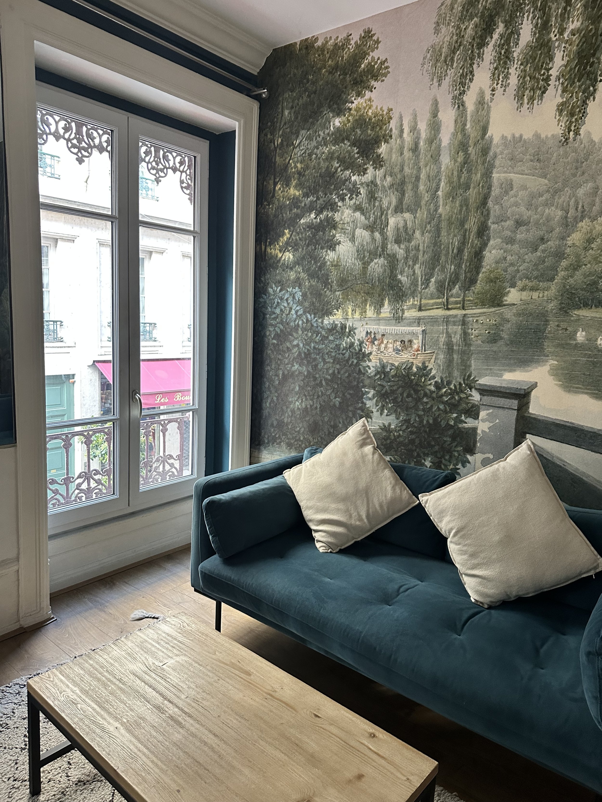 Elegantly furnished hotel room with tall windows and a teal velvet sofa overlooking a garden, a Supper Atlas curated stay