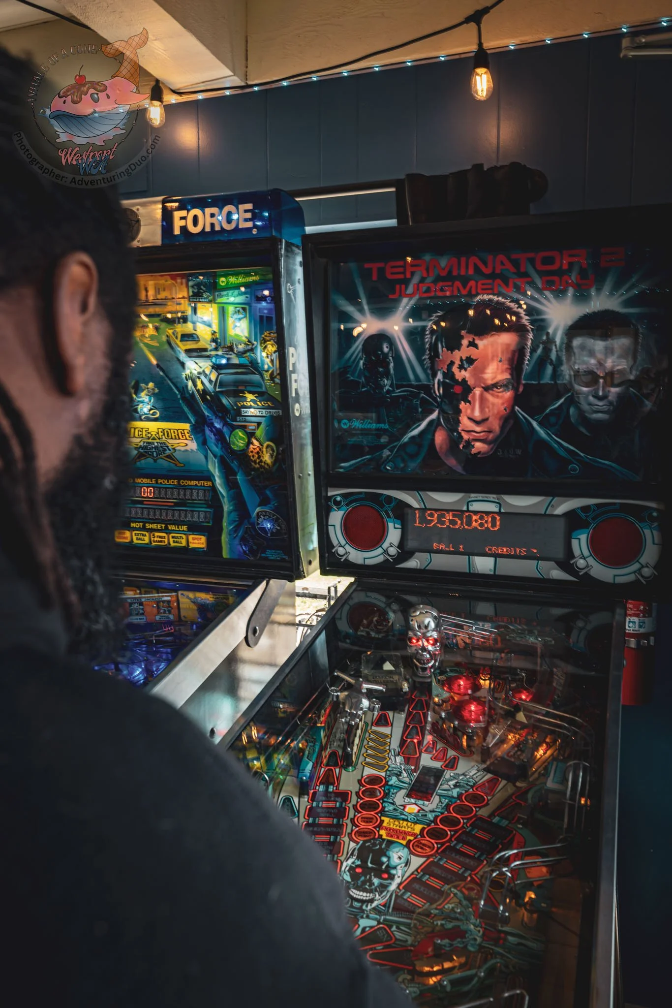 Close-up view of a pinball machine featuring artwork from the film 'Terminator 2: Judgment Day,' including characters and the title, with parts of the machine's playfield visible.