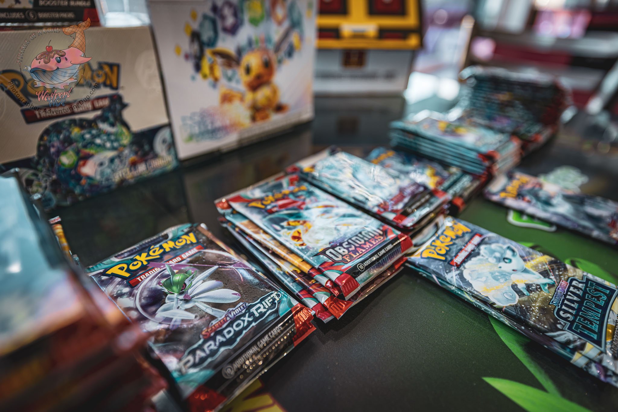 Stacked packs of Pokémon trading cards on display in a store, with some Pokémon box and booster packs visible.