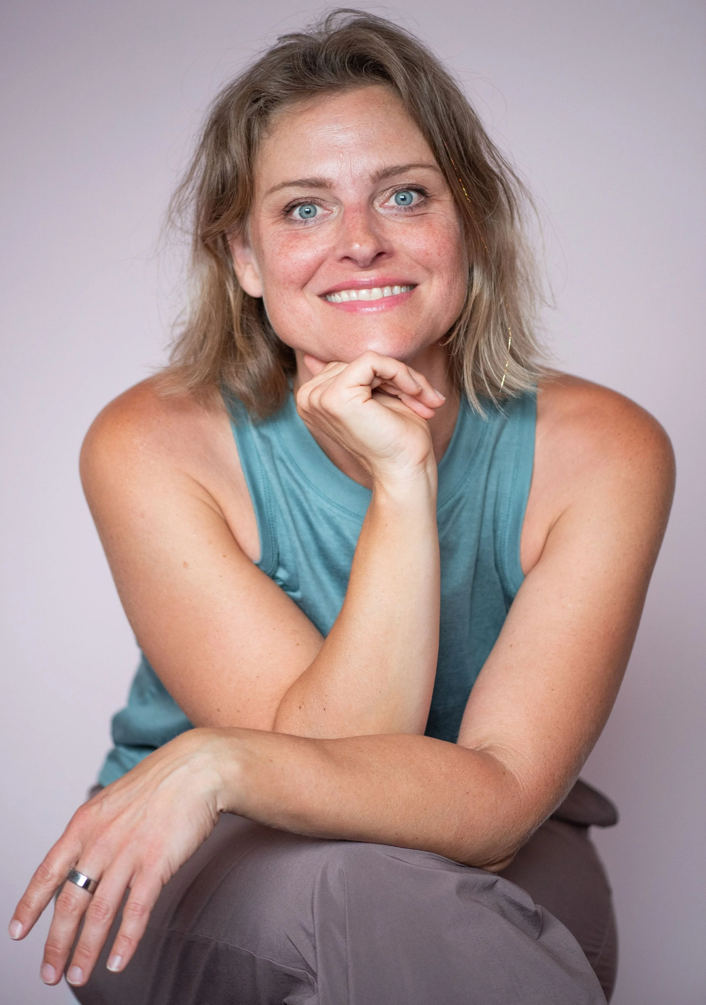 Victoria Steward smiling with chin resting on hand, wearing a teal sleeveless top, in a casual, welcome seeting.