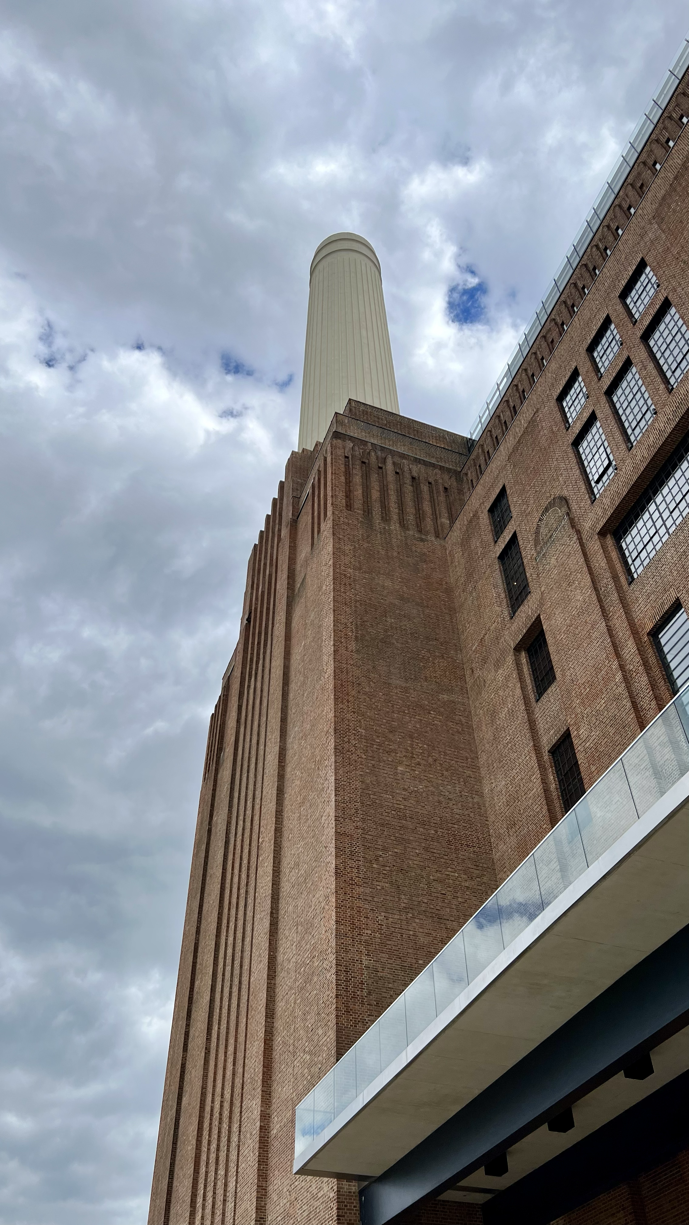A low-angle view of the Empire State Building's facade and spire against a cloudy sky during daytime.
