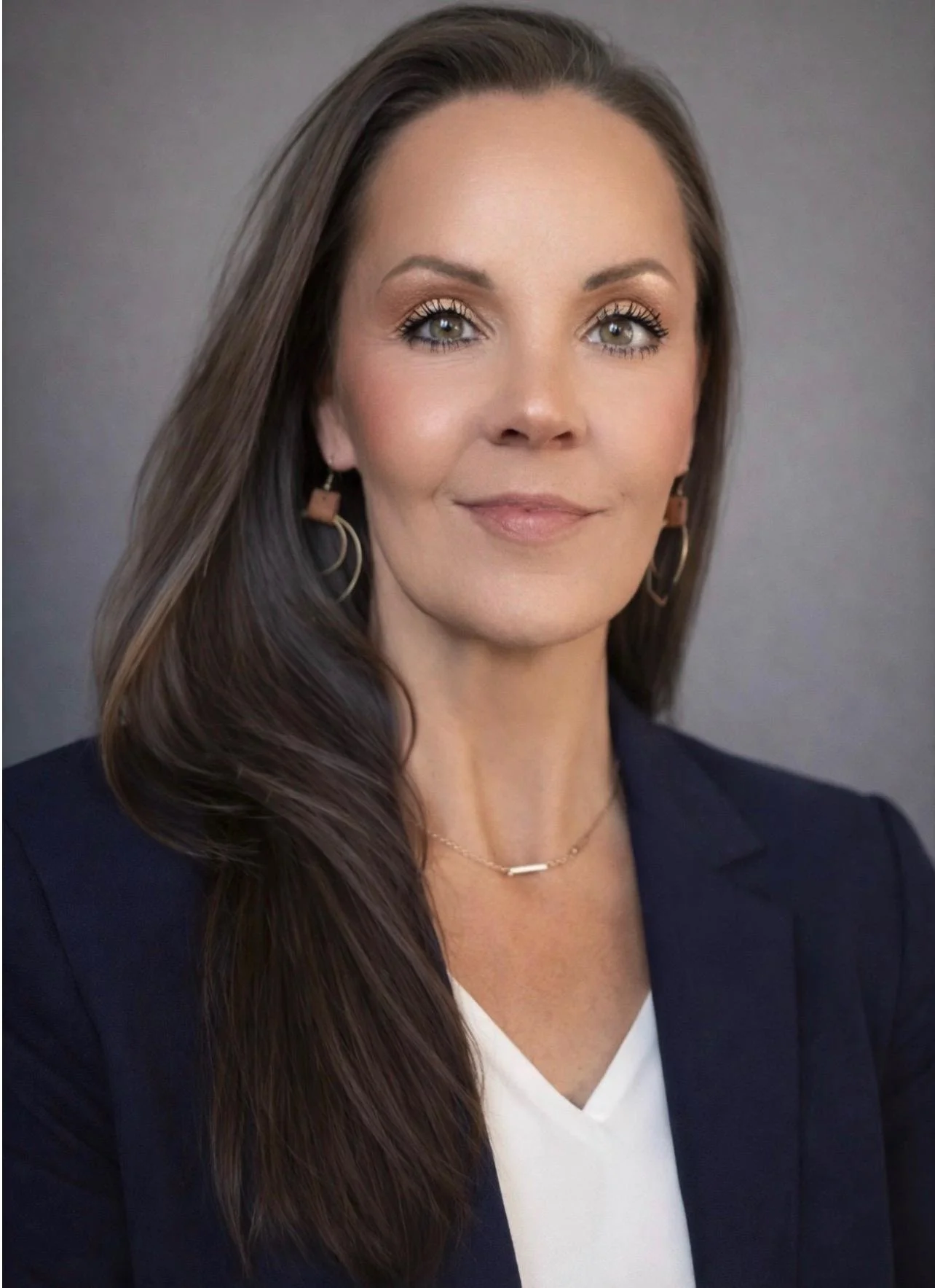 Woman with long brown hair and gold earrings.