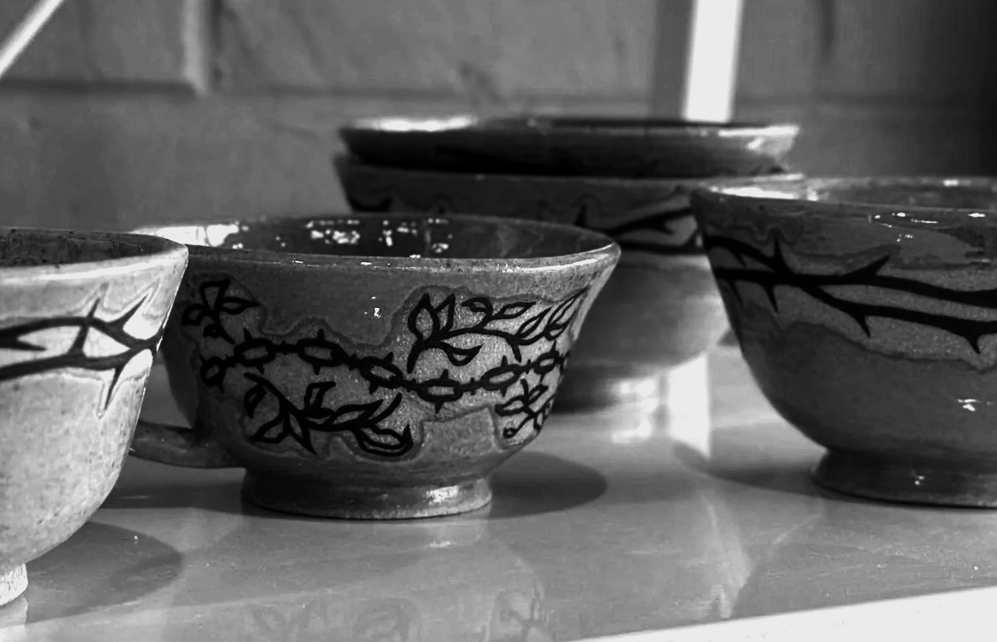 Black and white photo of several ceramic bowls with decorative patterns, arranged on a wooden surface.