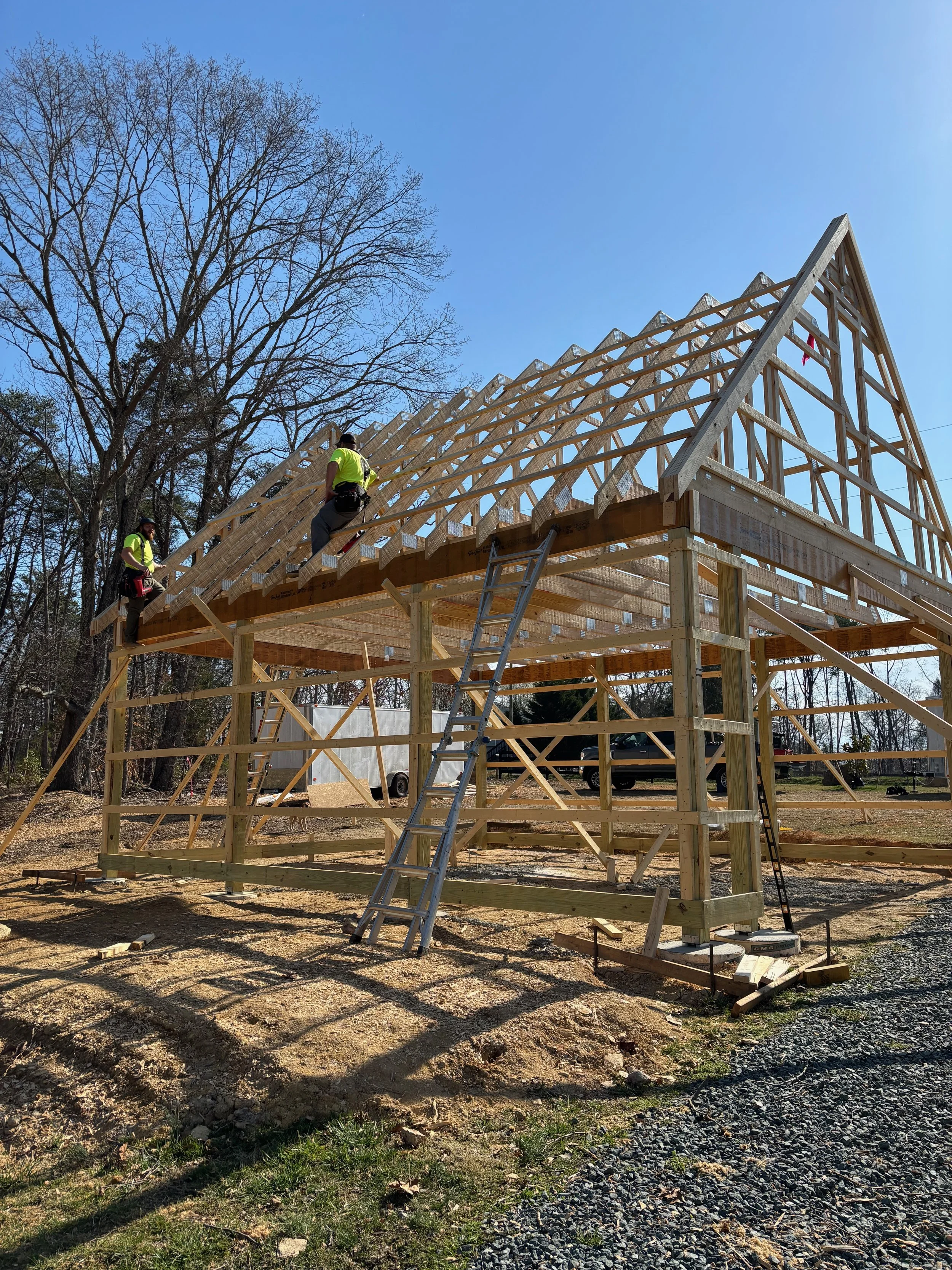 Construction workers building a wooden house frame outdoors on a clear sunny day.