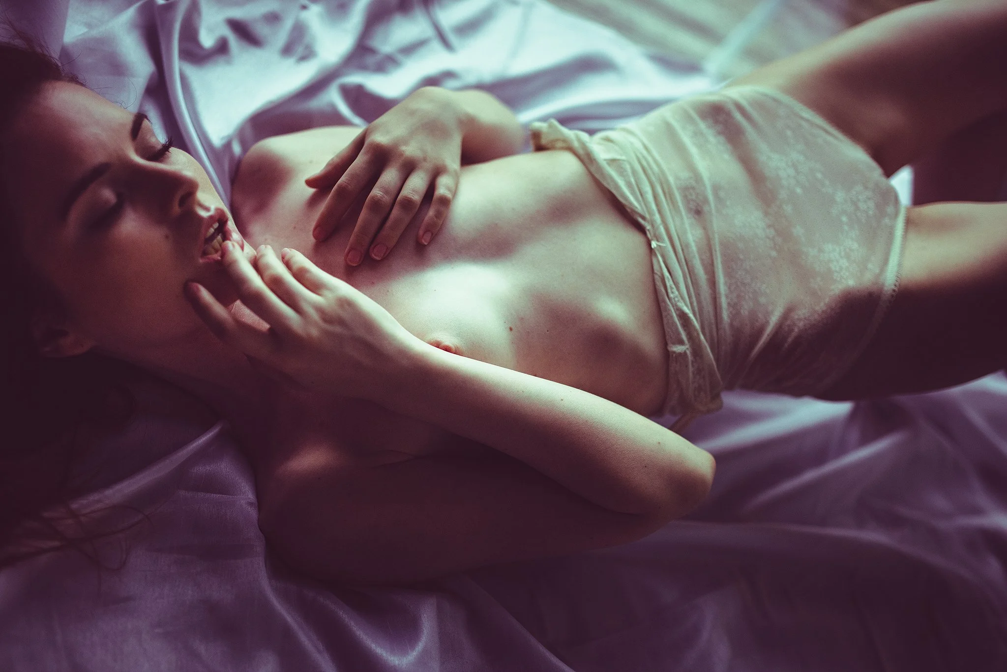 Eine Frau in Unterwäsche liegt auf einem Bett aus Seide und wirkt entspannt.