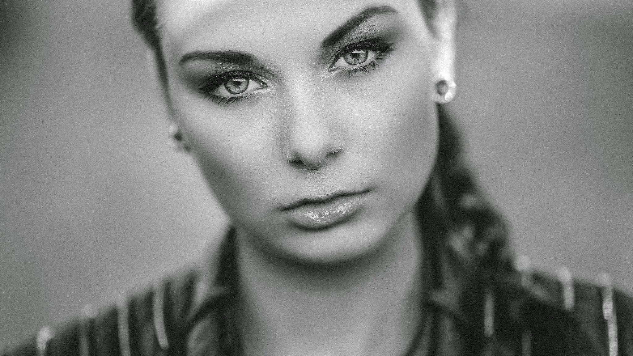 Schwarzweiß-Porträt einer Frau mit geflochtenem Haar, ausdrucksstarken Augen und Ohrringen.