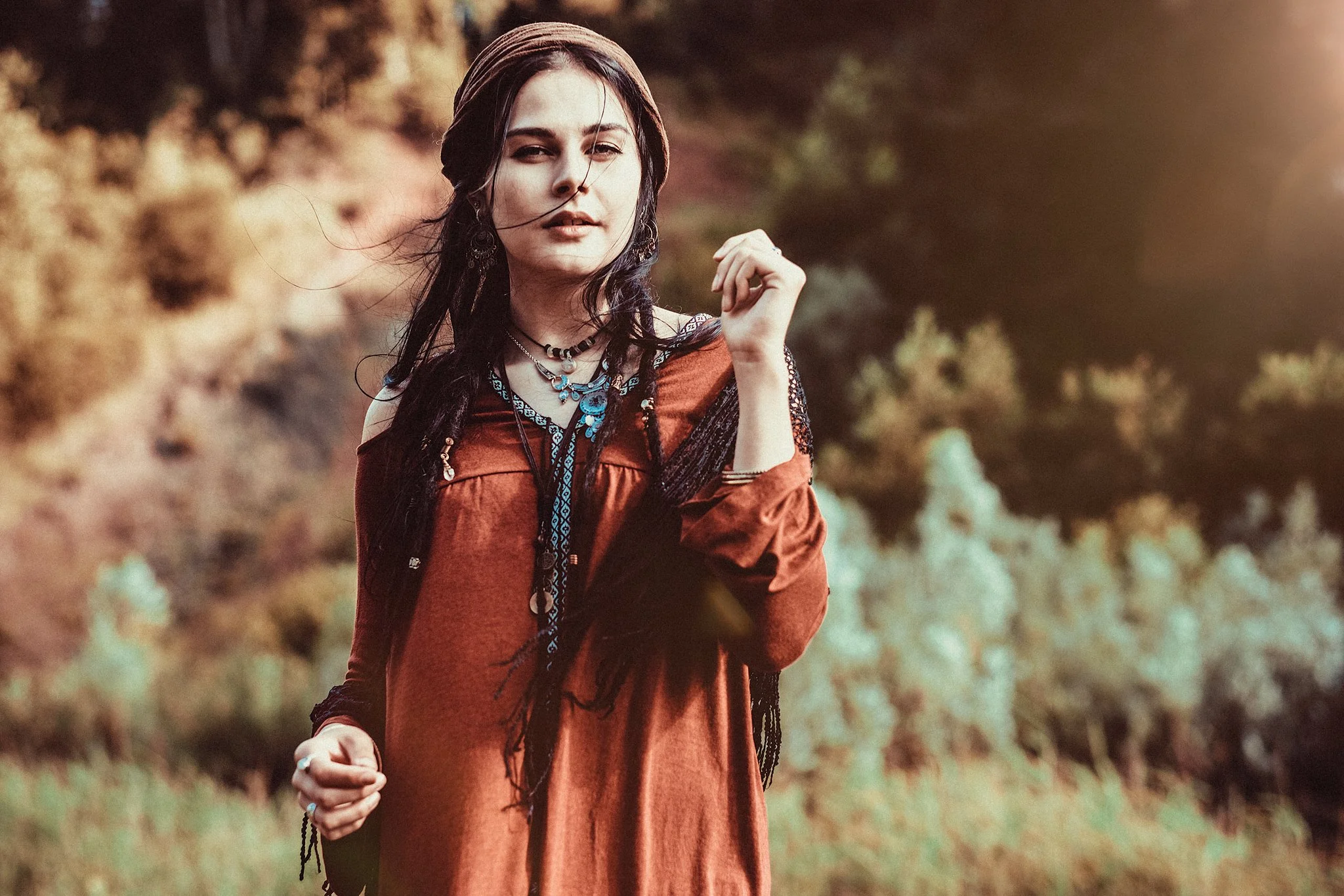 Frau in rotem Kleid und Stirnband im Freien, umgeben von Natur.