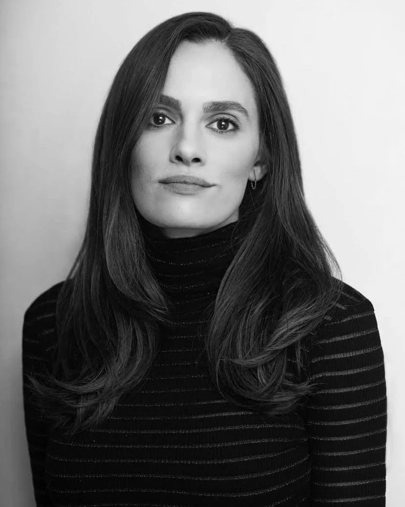 Black and white portrait of a woman with long hair wearing a striped turtleneck sweater, looking serious.