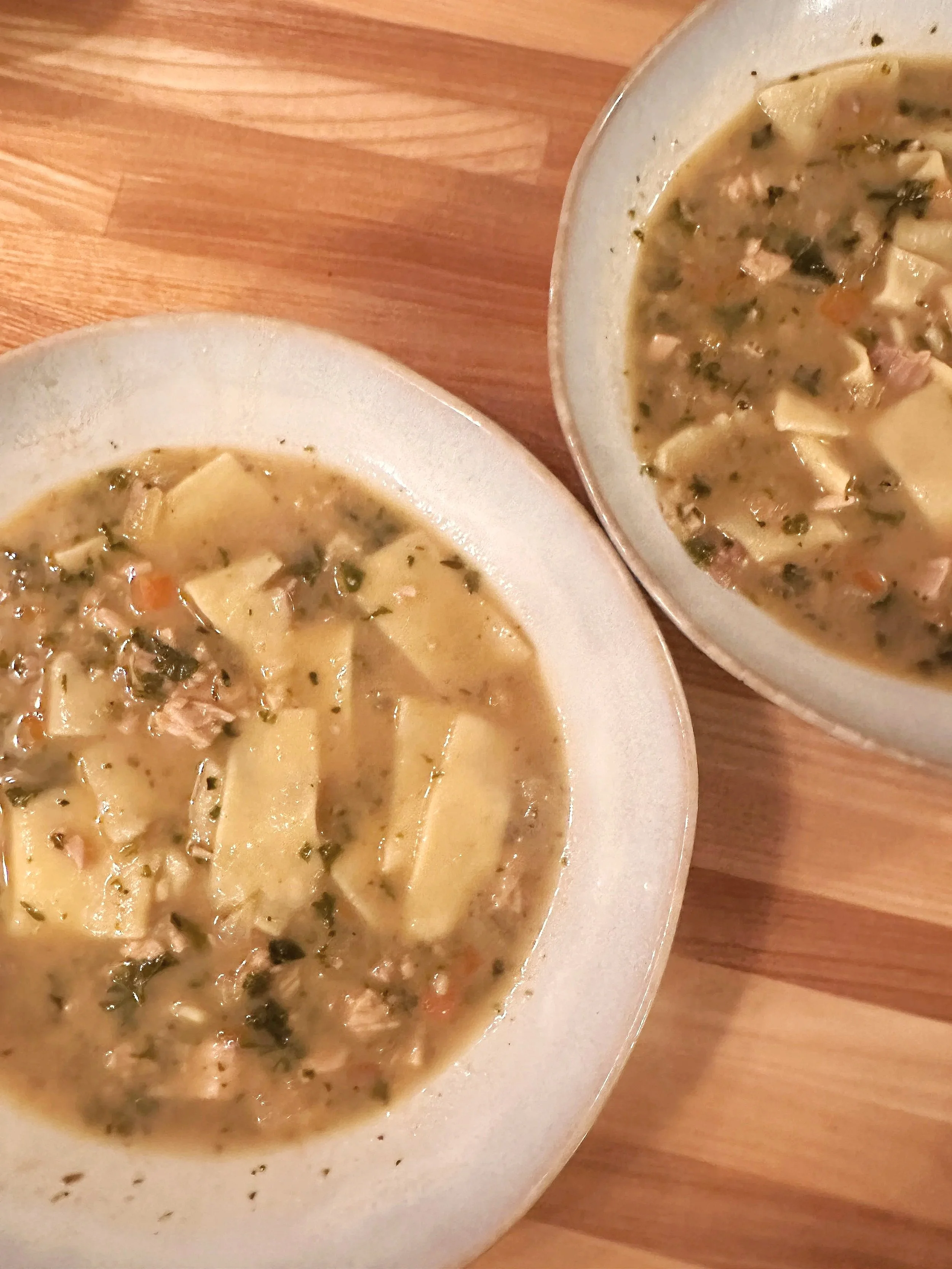 An image of two white bowls of chicken noodle soup