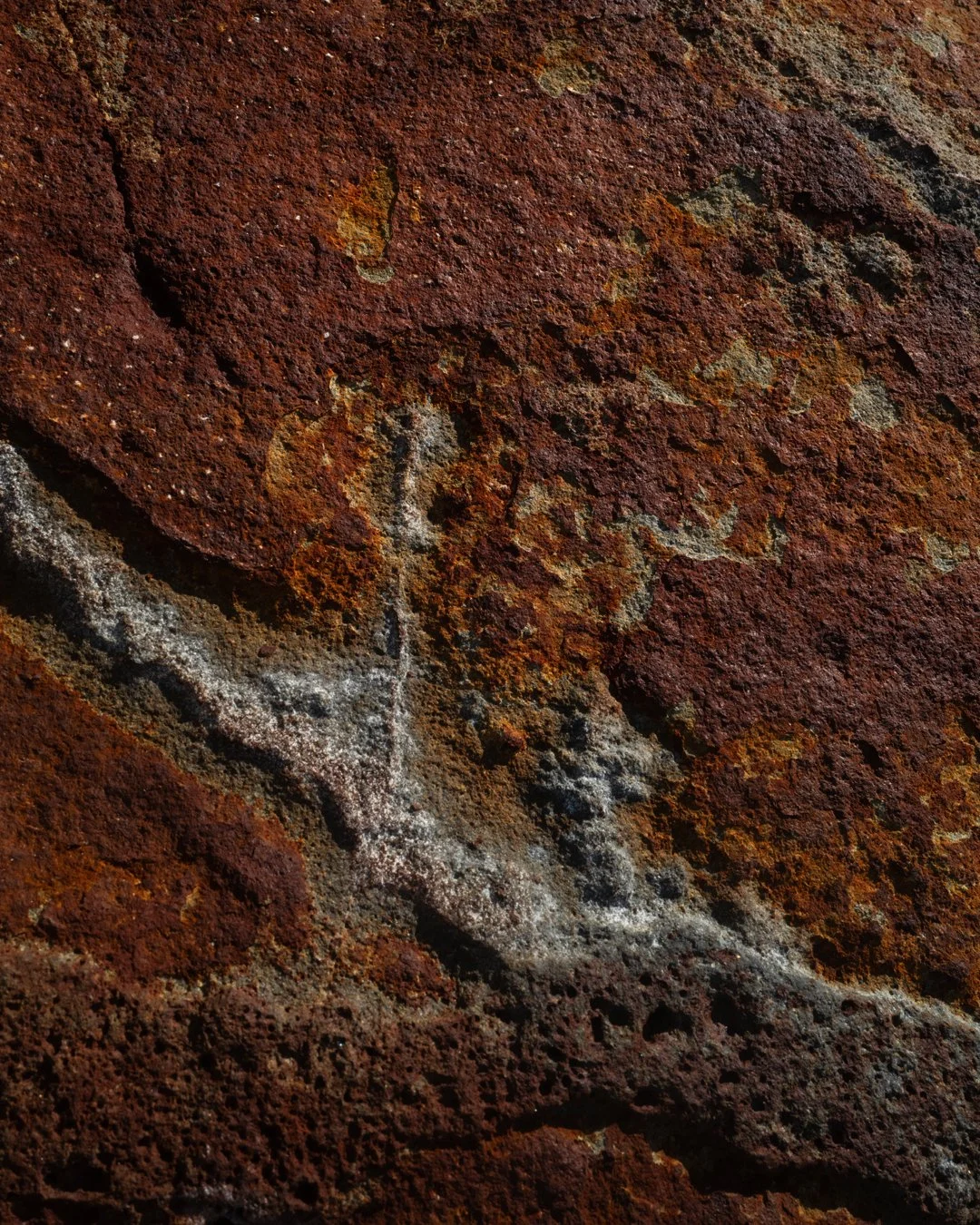 Close-up of a rusted, textured rock surface with white chalk markings and lines.