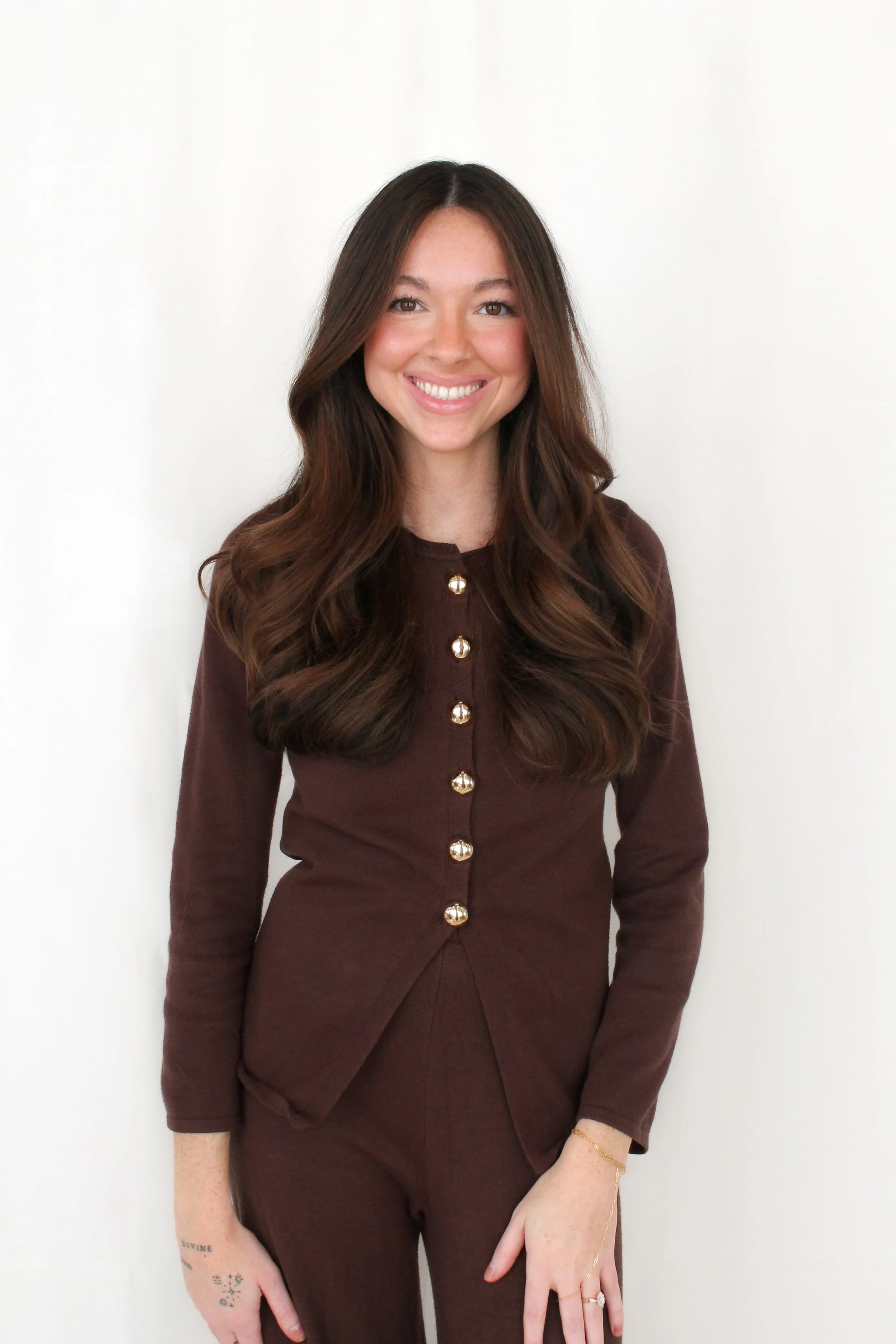 Woman in all brown outfit with brown hair smiling at the camera.