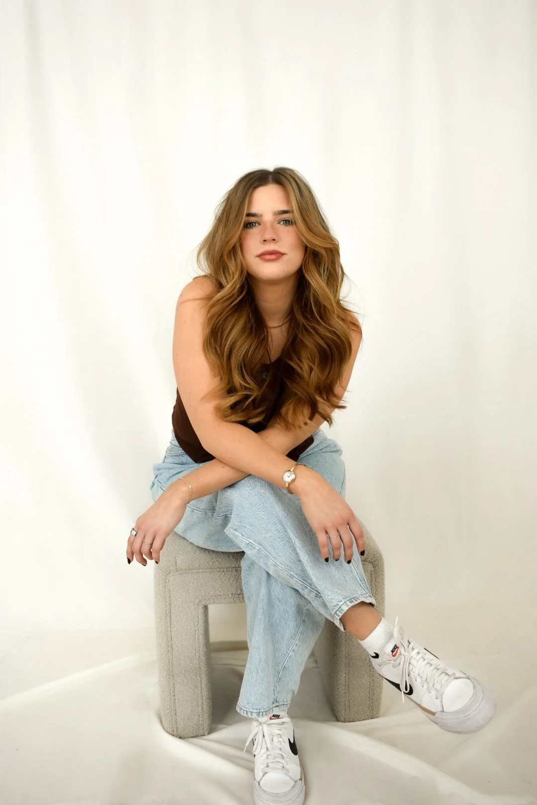 Woman sitting on bench with brown hair smirking.