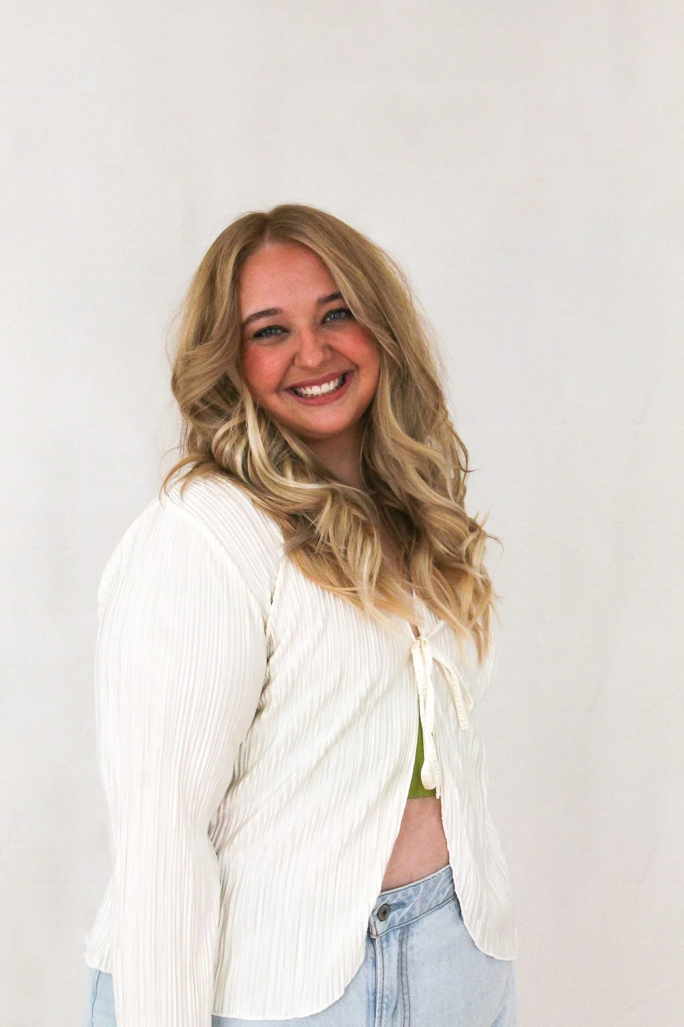 Woman with blonde hair in a white shirt smiling at the camera.