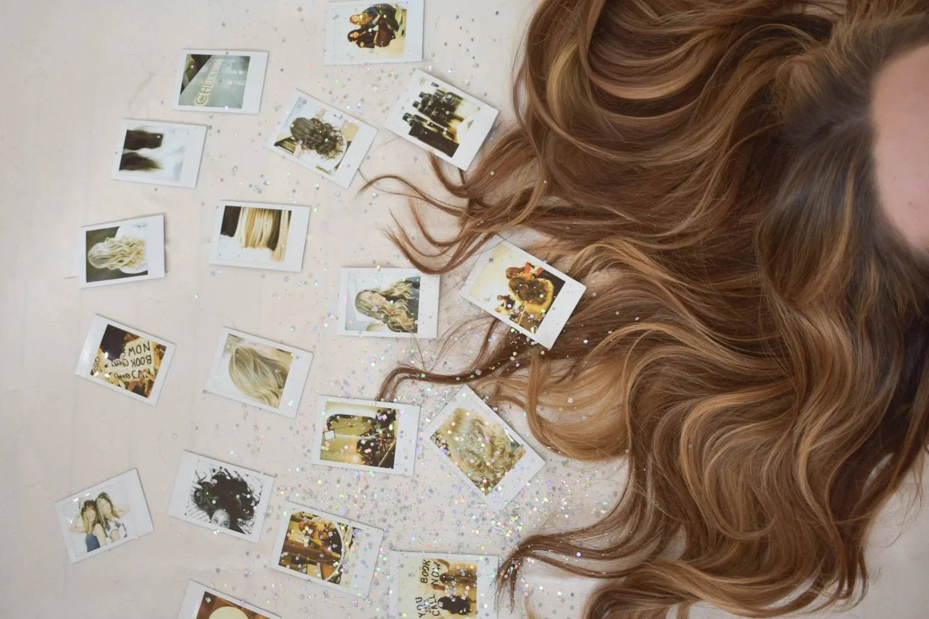 Polaroid pictures laid on the ground with hair spread out and glitter.