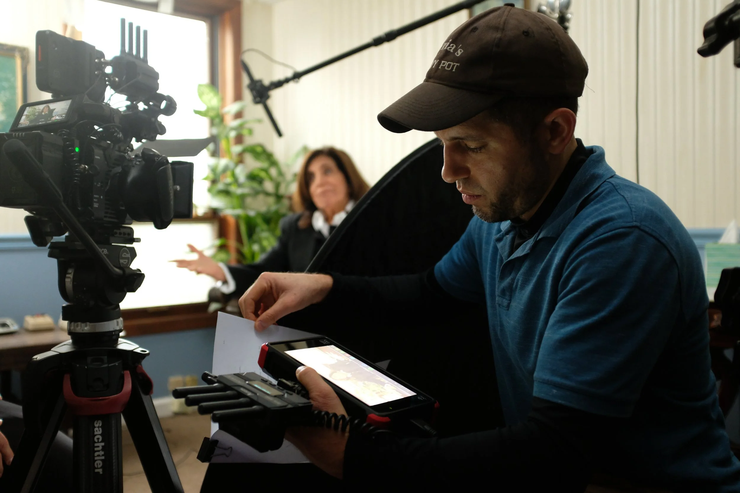 Filmmaker operating camera equipment while woman speaks in a studio setting.
