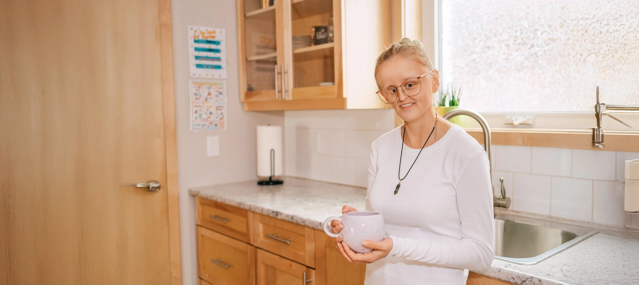 Woman leaning against counter holding mug of coffee