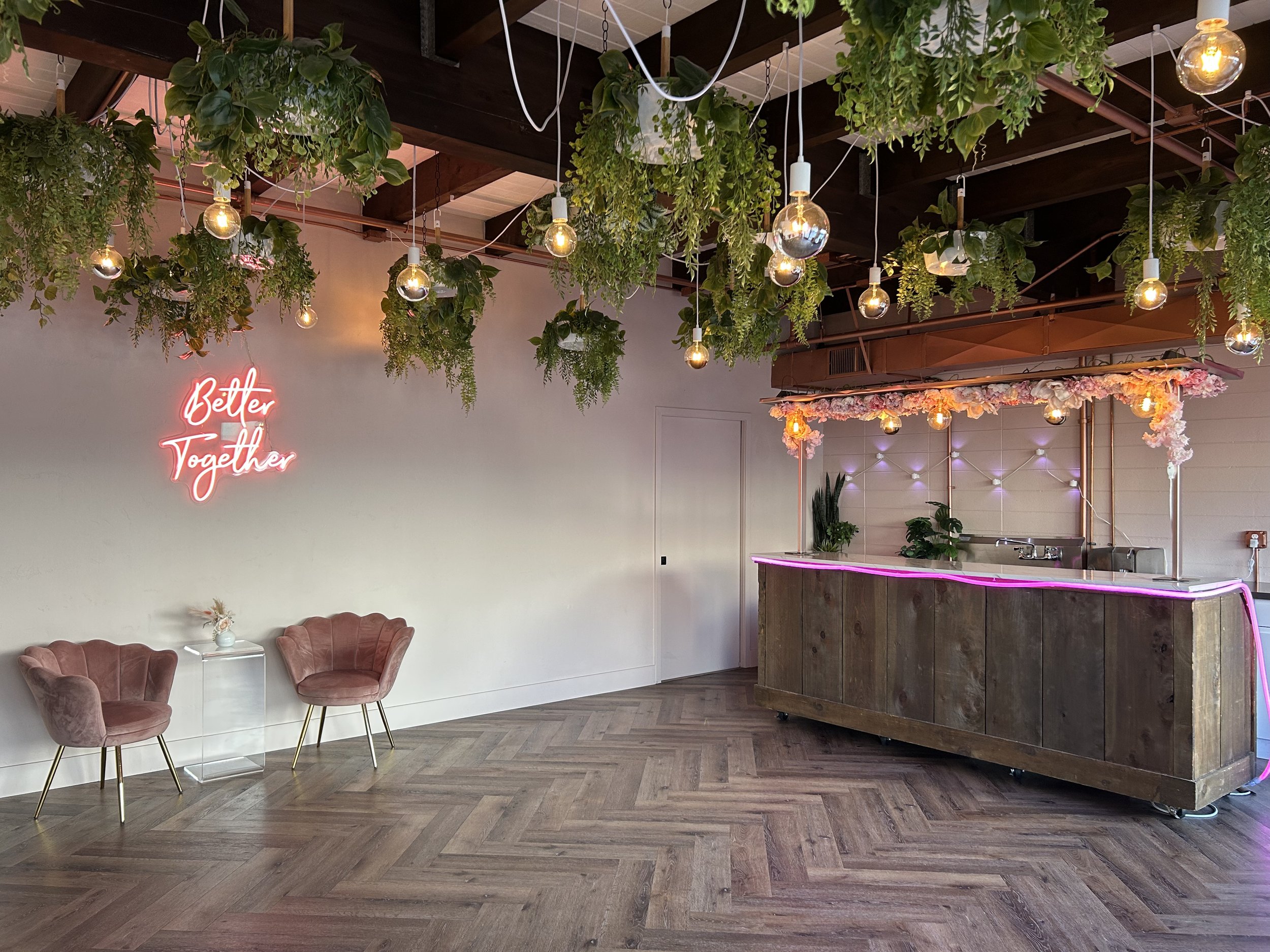A bride sitting at a cocktail table with a bouquet of fall colored flowers in frot of a wall of mirrors