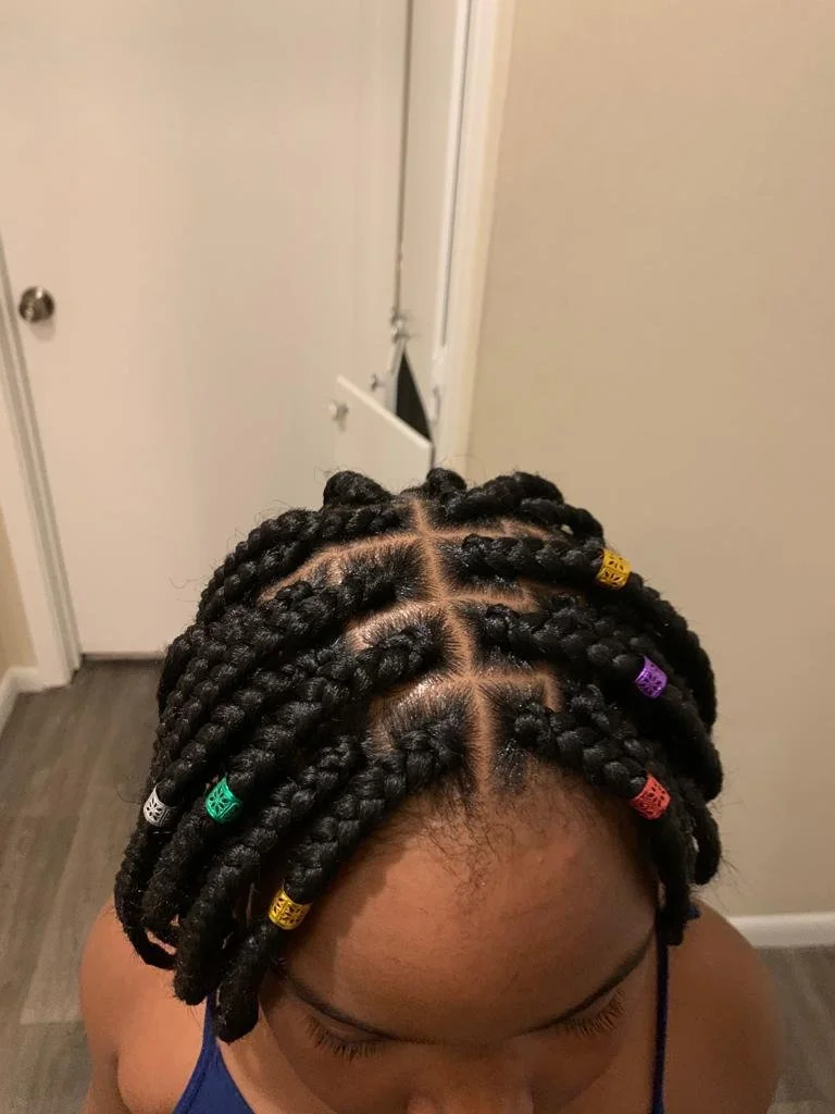 Top view of a person with braided hair decorated with colorful beads