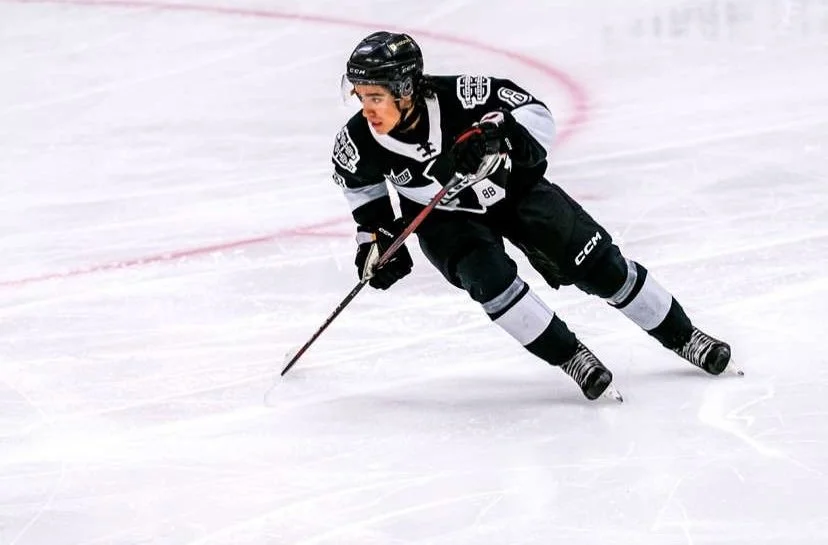 Un joueur de hockey en noir et blanc glisse rapidement sur la glace lors d'un match.