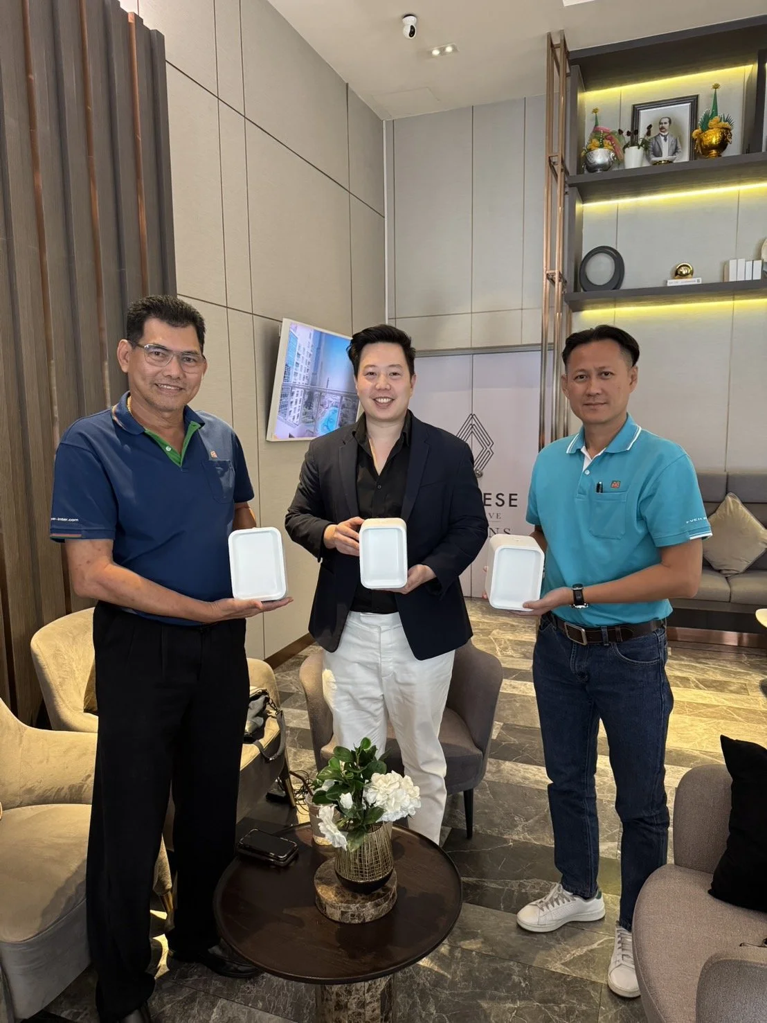 Founder of Blue Oak, Pattana Lee (center) with his co-founders, all holding up the product in a hotel room.