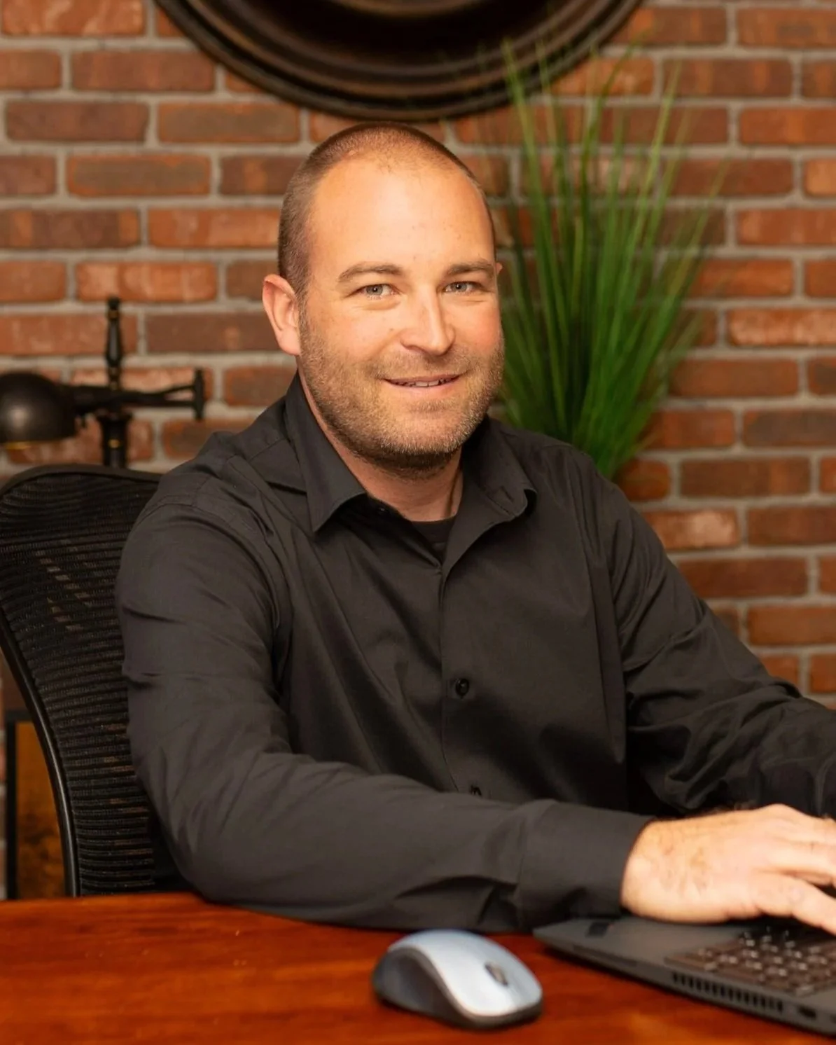 Kyle Fletcher sitting at a desk in front of a brick wall