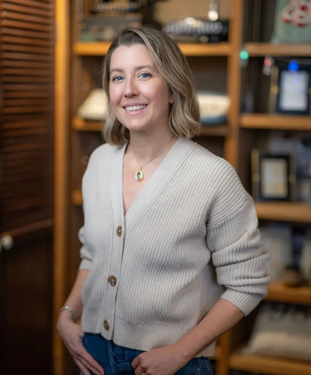 Image of writer standing in front of bookshelf and smiling