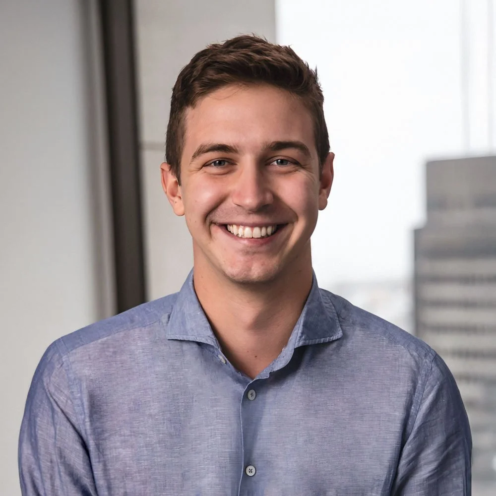 Erik Fischer, President of Lighthouse, smiling in an office setting with a window and cityscape in the background.