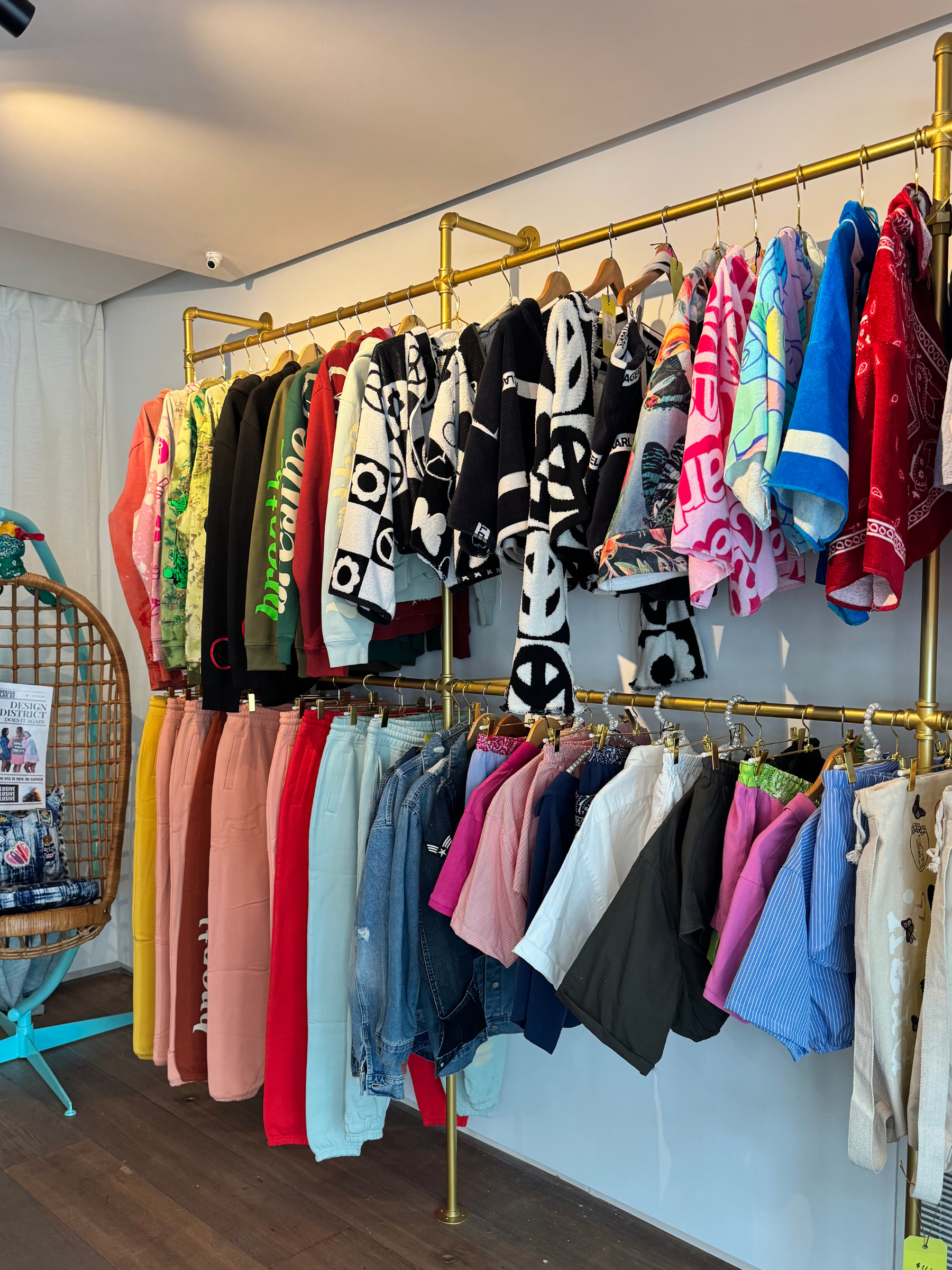 Clothing rack with various children's t-shirts, hoodies, and pants on hangers in a store.