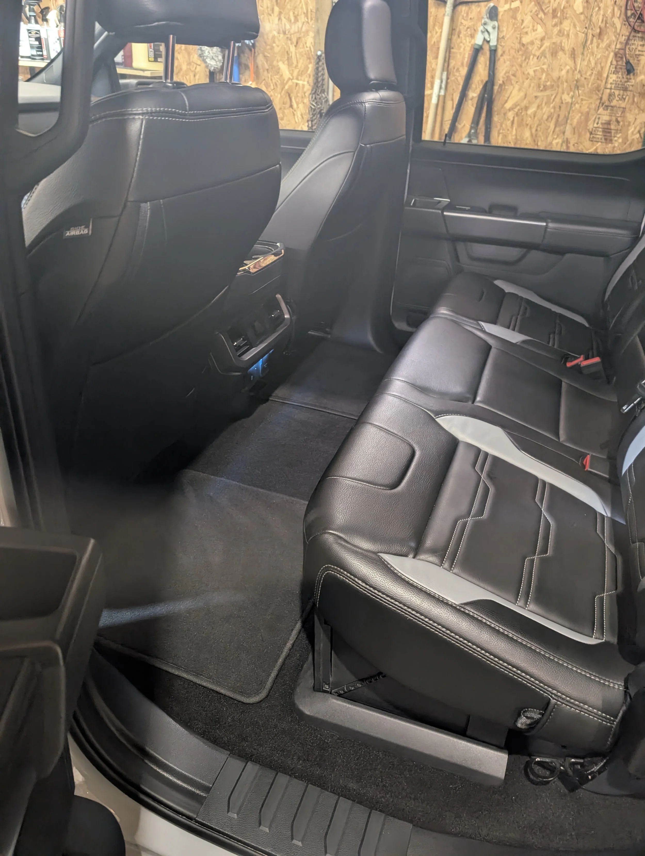 The interior of a vehicle showing the back seats, black leather seats, and the front seatbacks.
