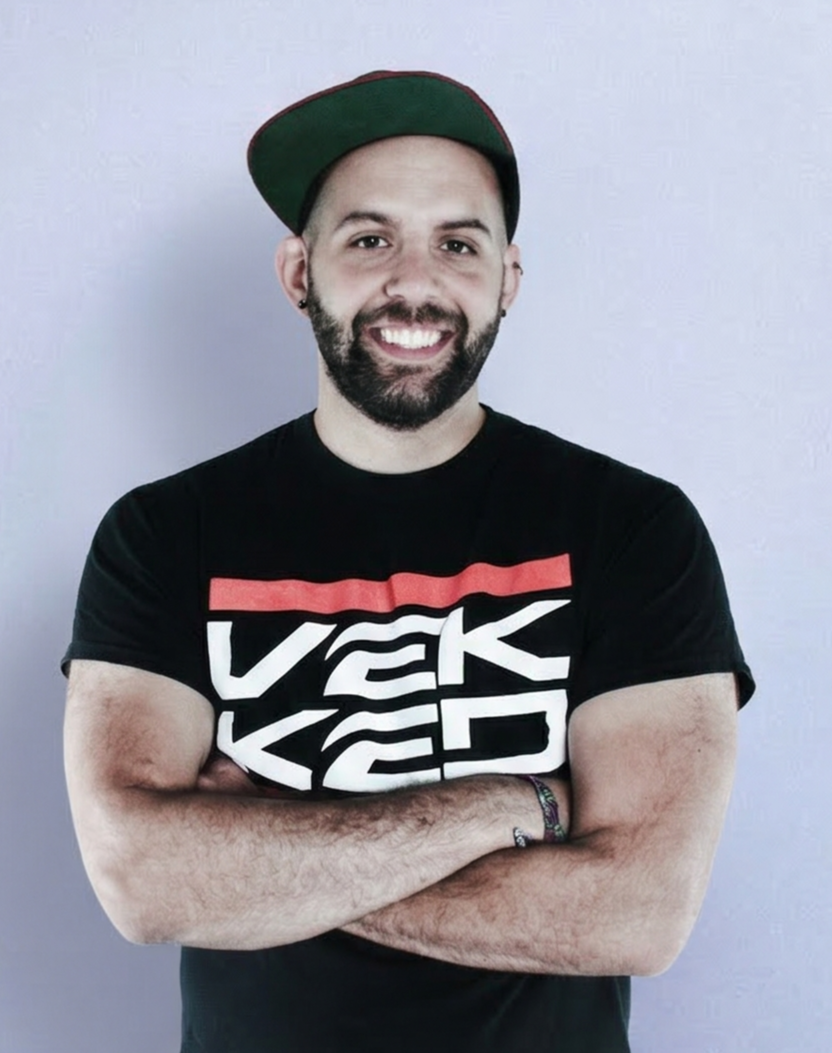 DJ VEKKED performing at a turntable setup, concentrating on his mix during a live DJ set.