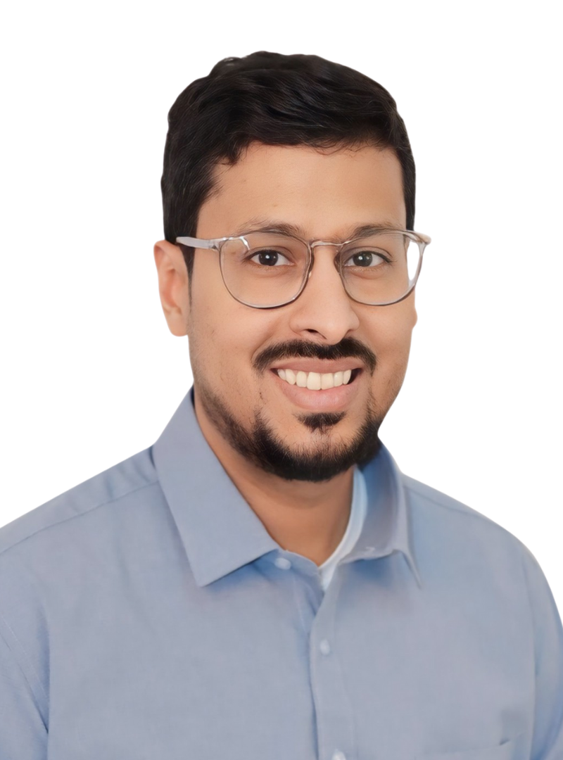 A smiling man with dark hair, glasses, and a beard, wearing a light blue collared shirt, posing against a black background.