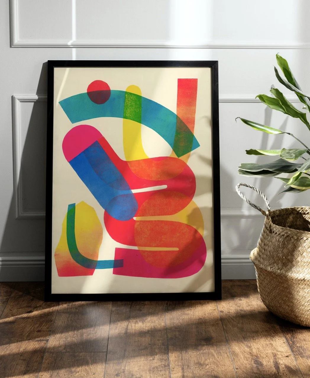 Spring bounce print shown in a black frame. Plant to the right of the artwork.