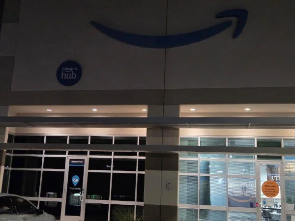 Amazon Hub storefront at night with illuminated windows and a dark sky