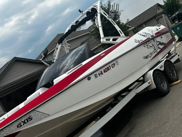 White and red boat on a trailer parked in a driveway.