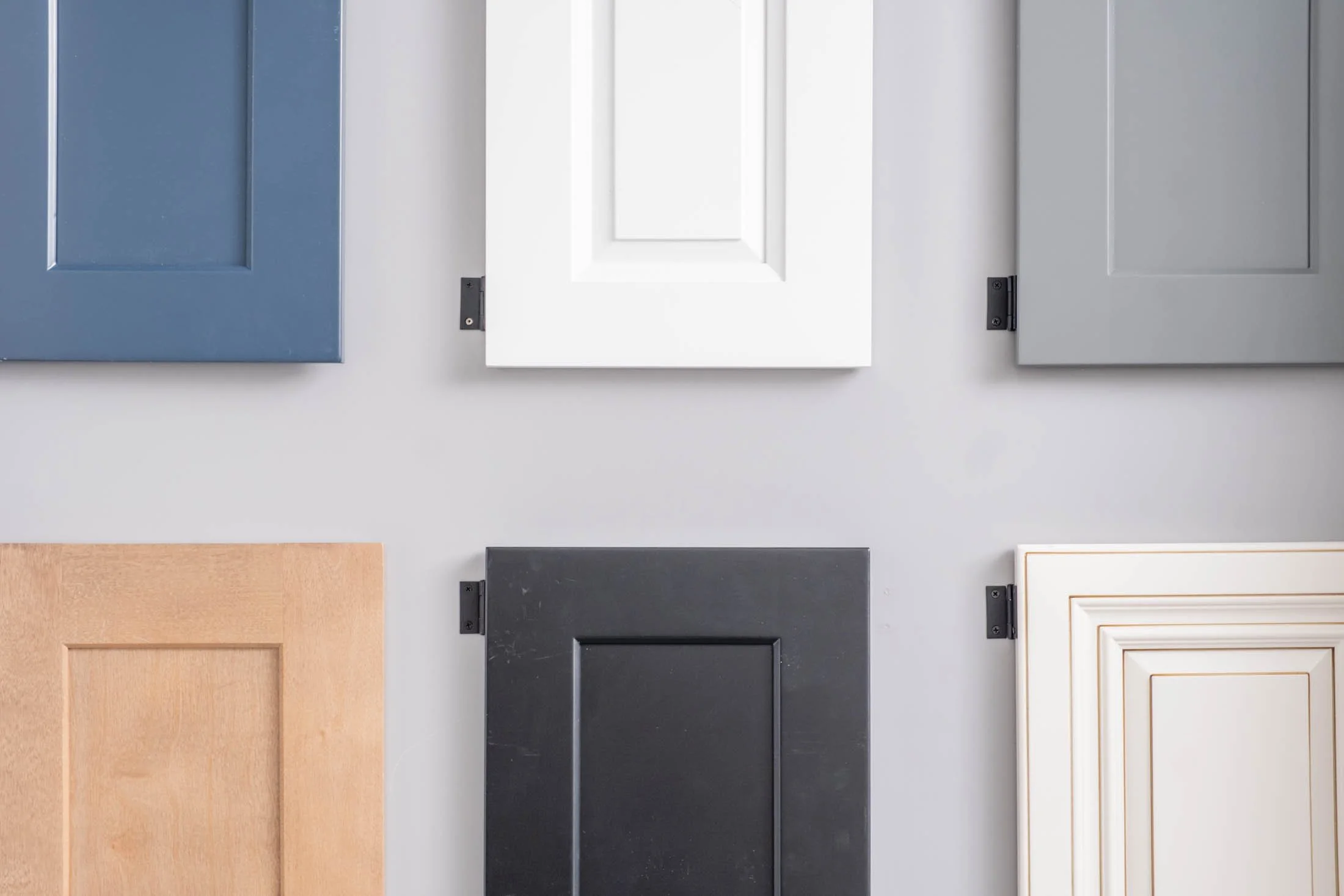 Six different cabinet doors in various colors and finishes arranged on a wall.