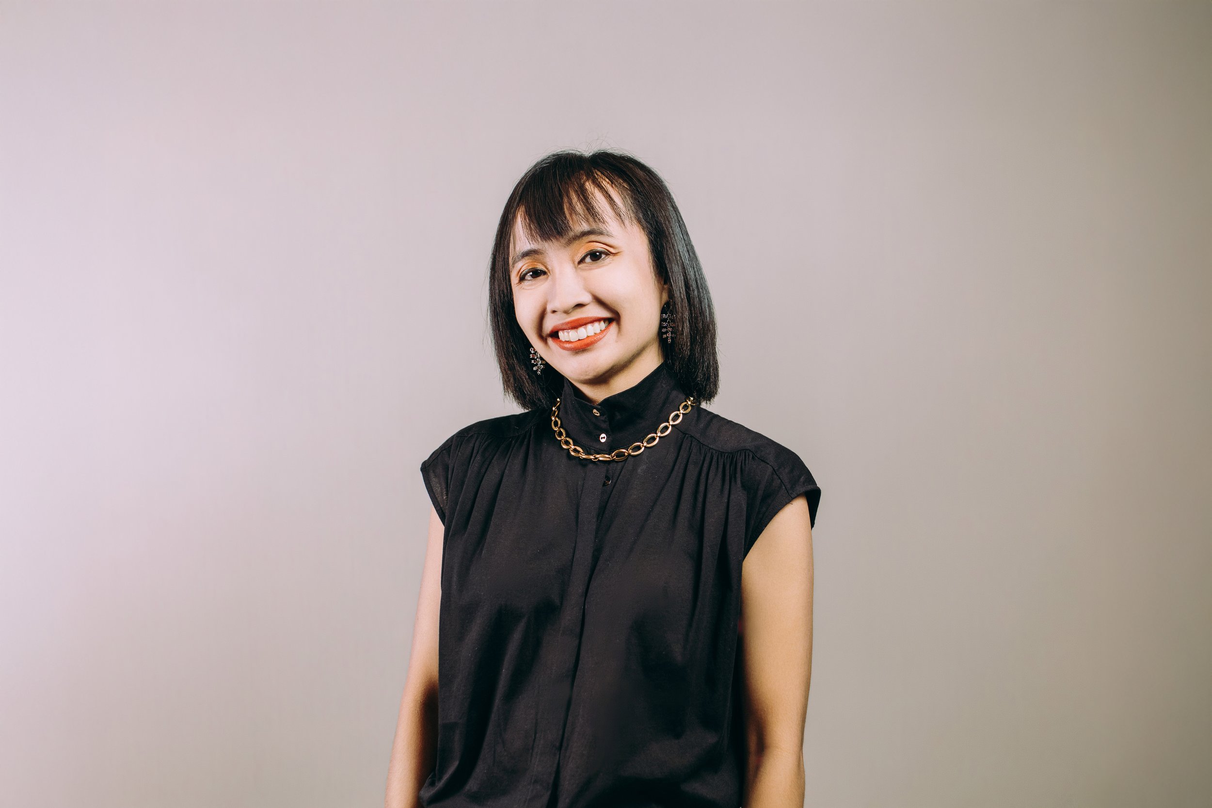 Smiling person wearing a burgundy shirt with button details, posing against a light blue background.