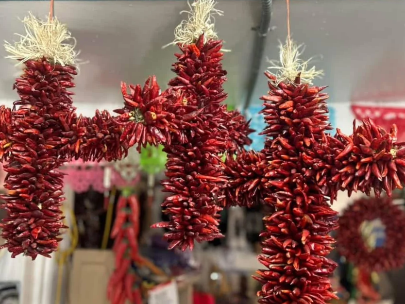 A decorative hanging ornament made of dried red chili peppers tied together in bundles, arranged in a star shape, and hung with string.