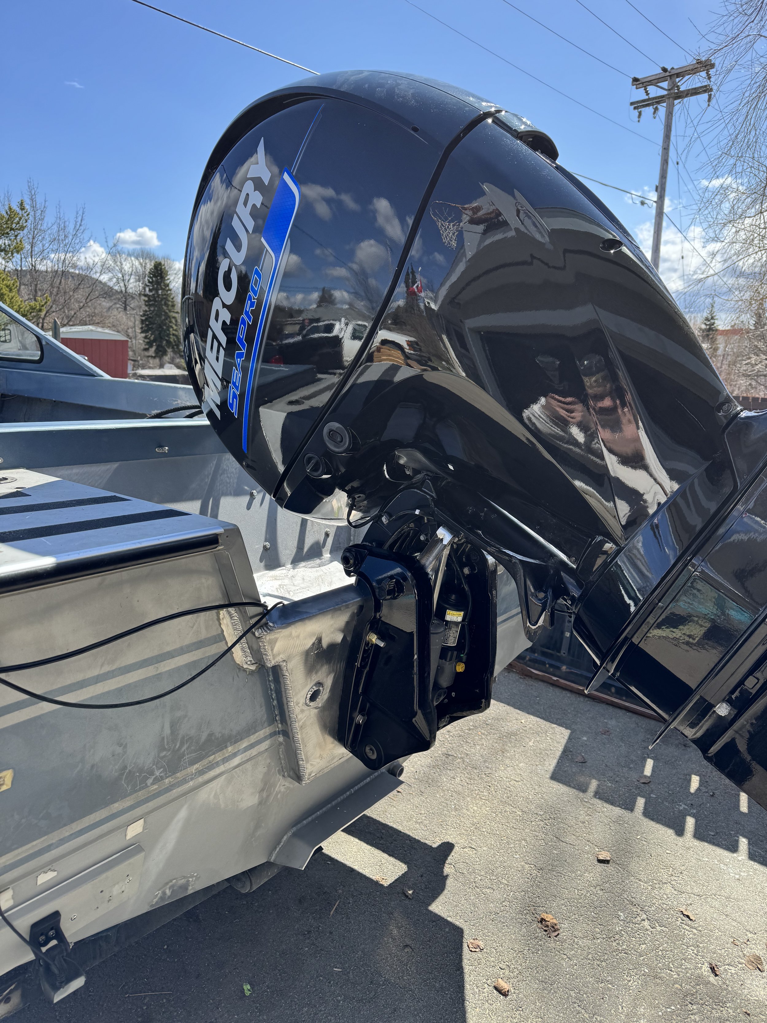 Mercury SeaPro outboard motor attached to a boat, parked outdoors on a sunny day.