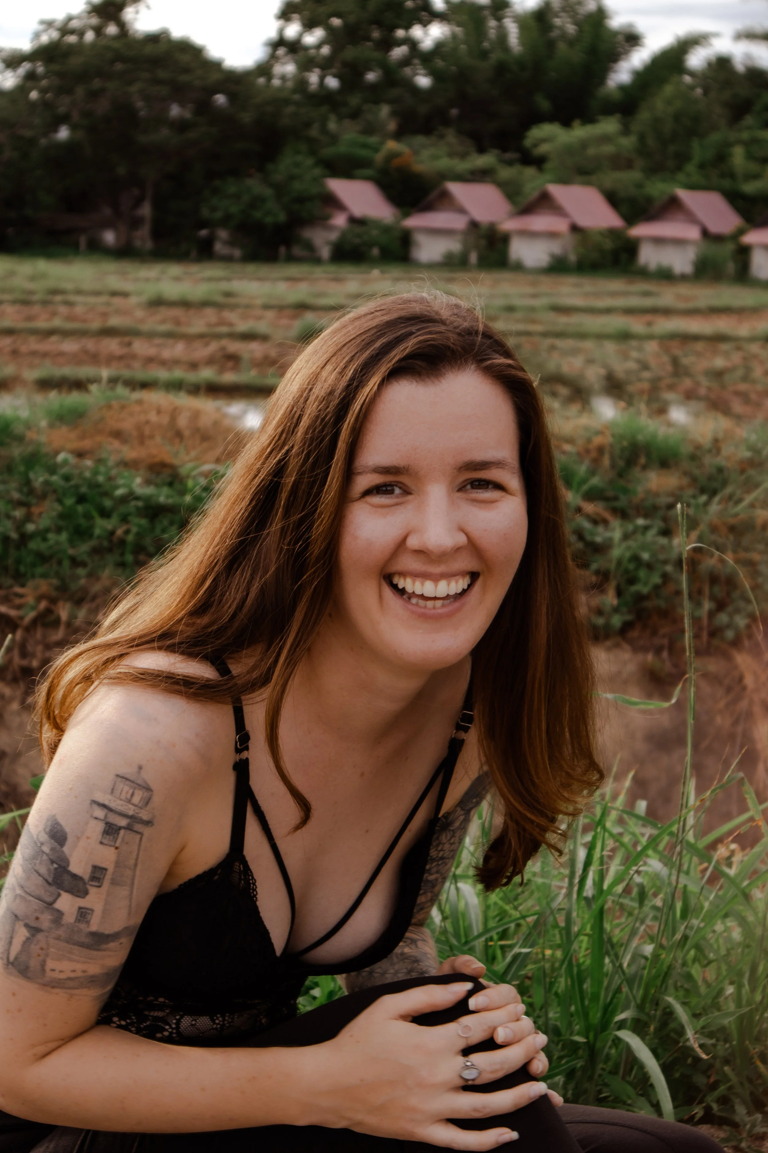 woman sitting in a rice field smiling with confidence