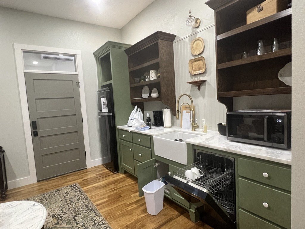 Custom green kitchen cabinetry with open shelving