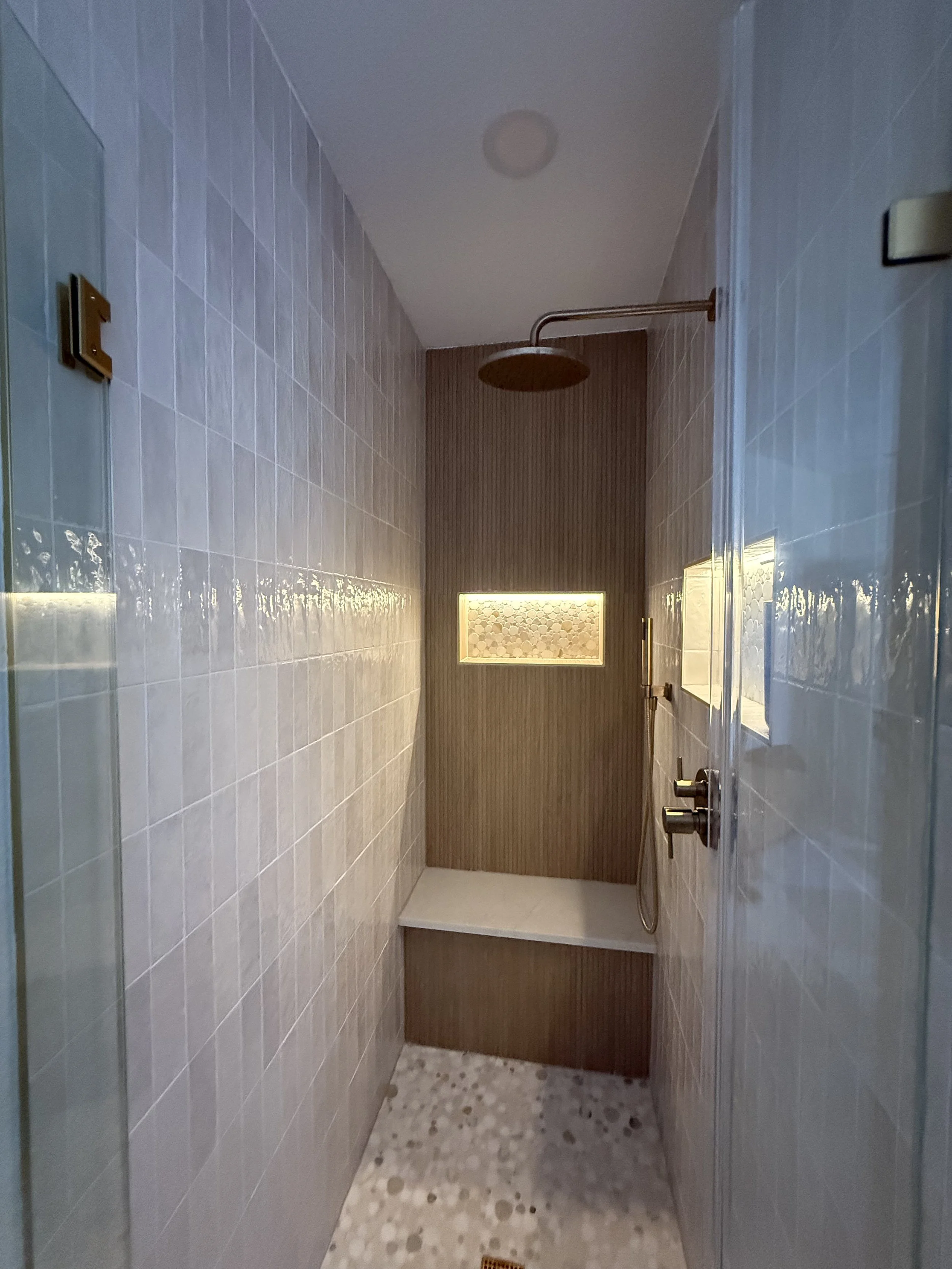 Modern walk-in shower with tiled walls, a rain showerhead, and a built-in niche with lighting.