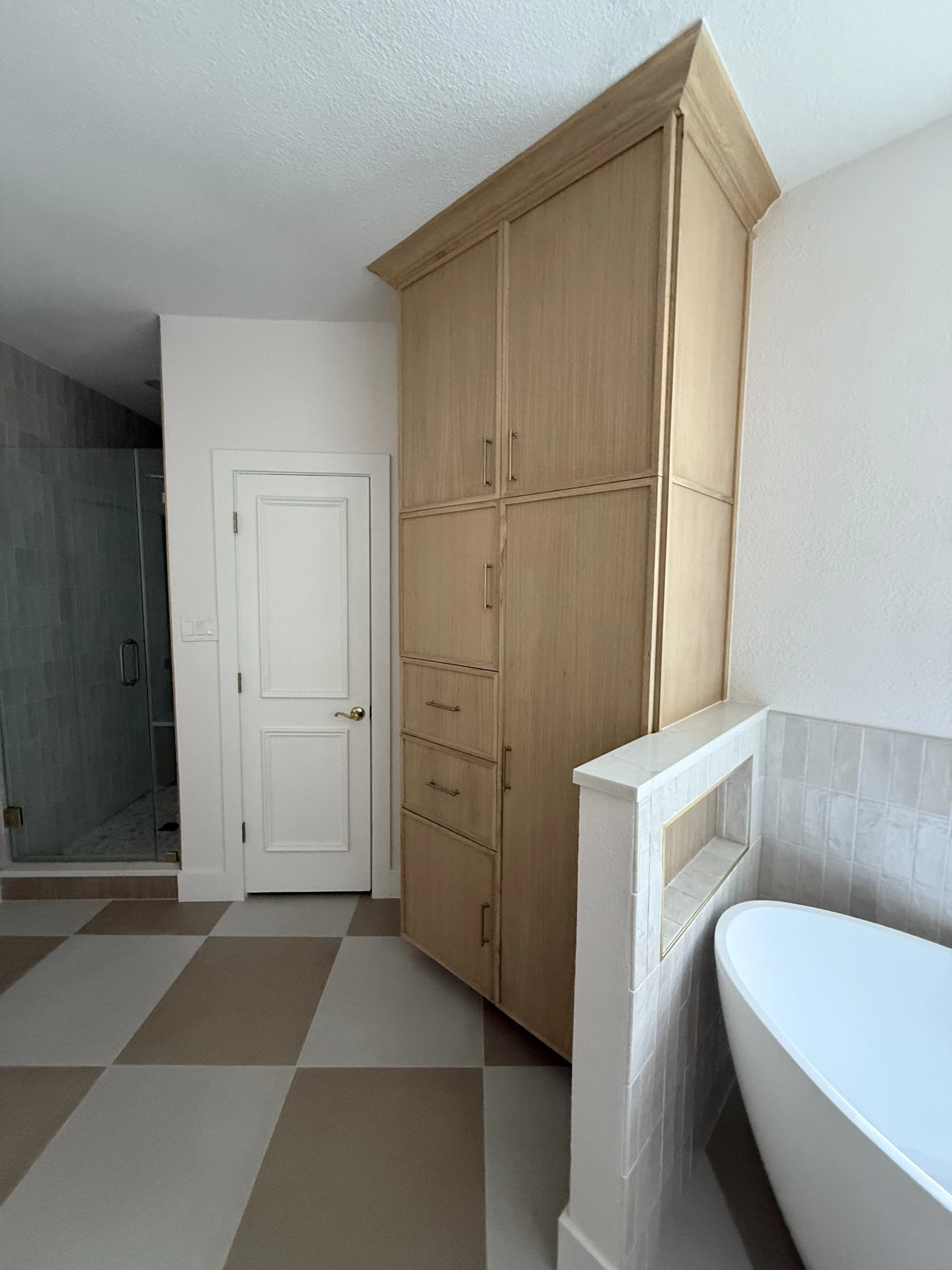 Bathroom with wooden cabinets, a white door, a glass-enclosed shower, and a bathtub.